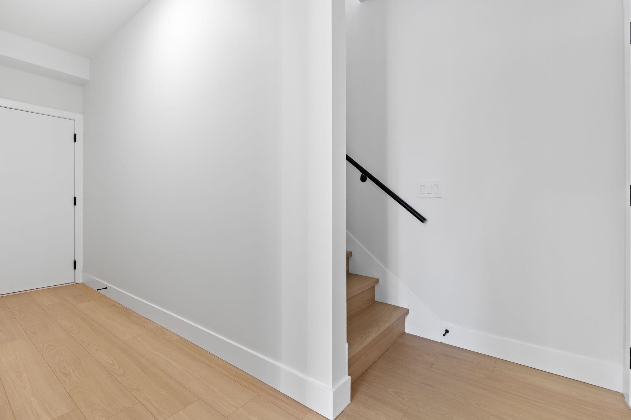 Clearbrook Commons – Interior entryway hallway featuring light wood flooring, white interior doors, and wooden staircase steps.
