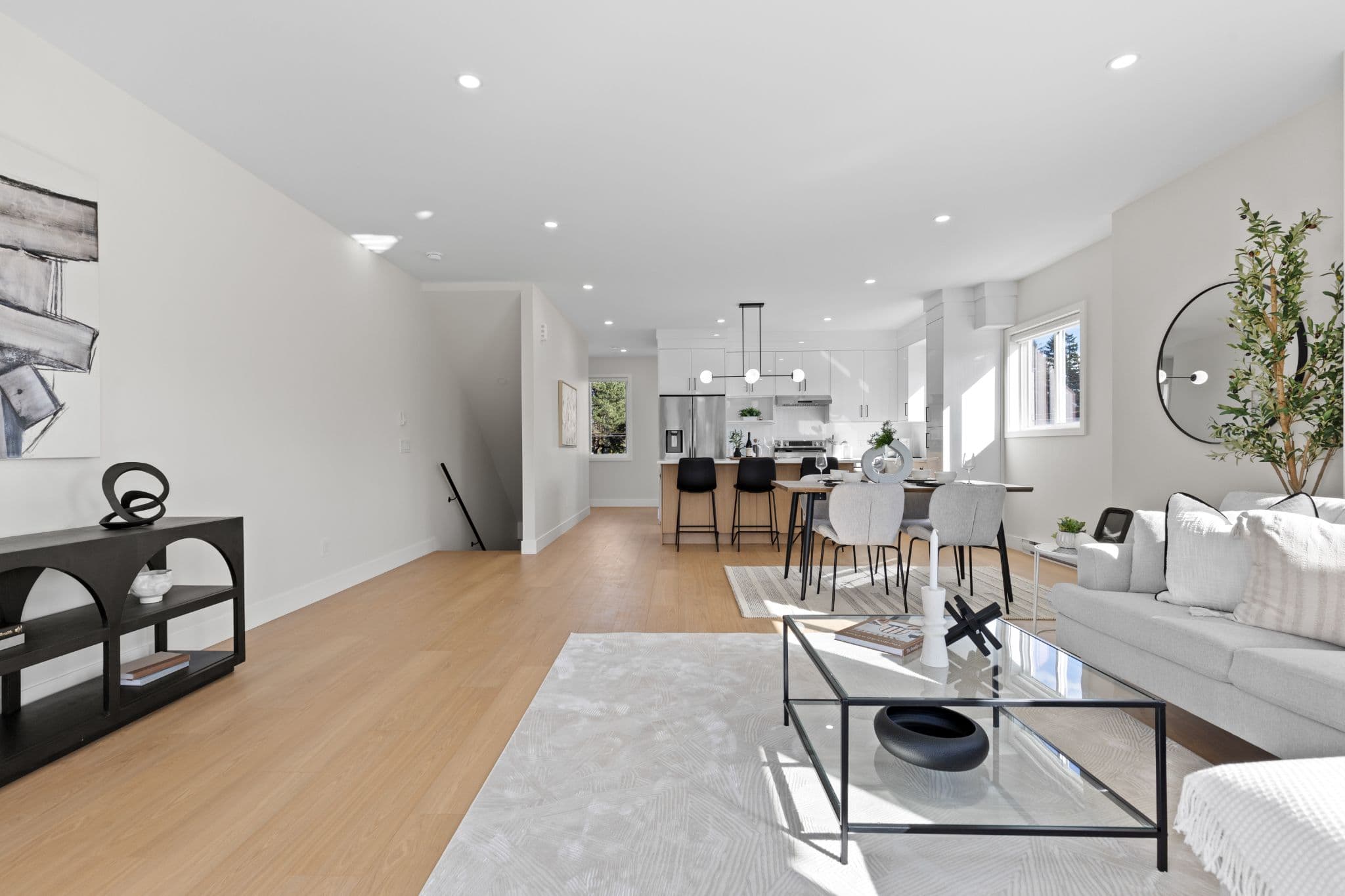 Clearbrook Commons – Broad view of open main floor layout connecting living room, dining space, and background kitchen island.