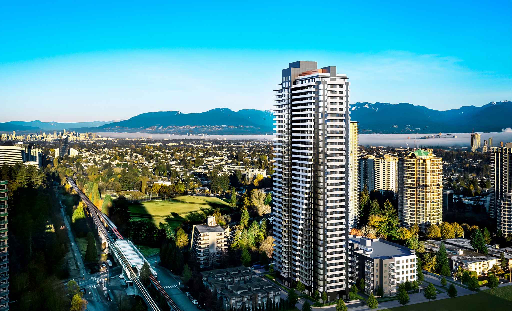 Perla Condos – An aerial drone view over the city showing the tower rising above surrounding low-rise buildings, a park with a golf course, and mountains in the distance.