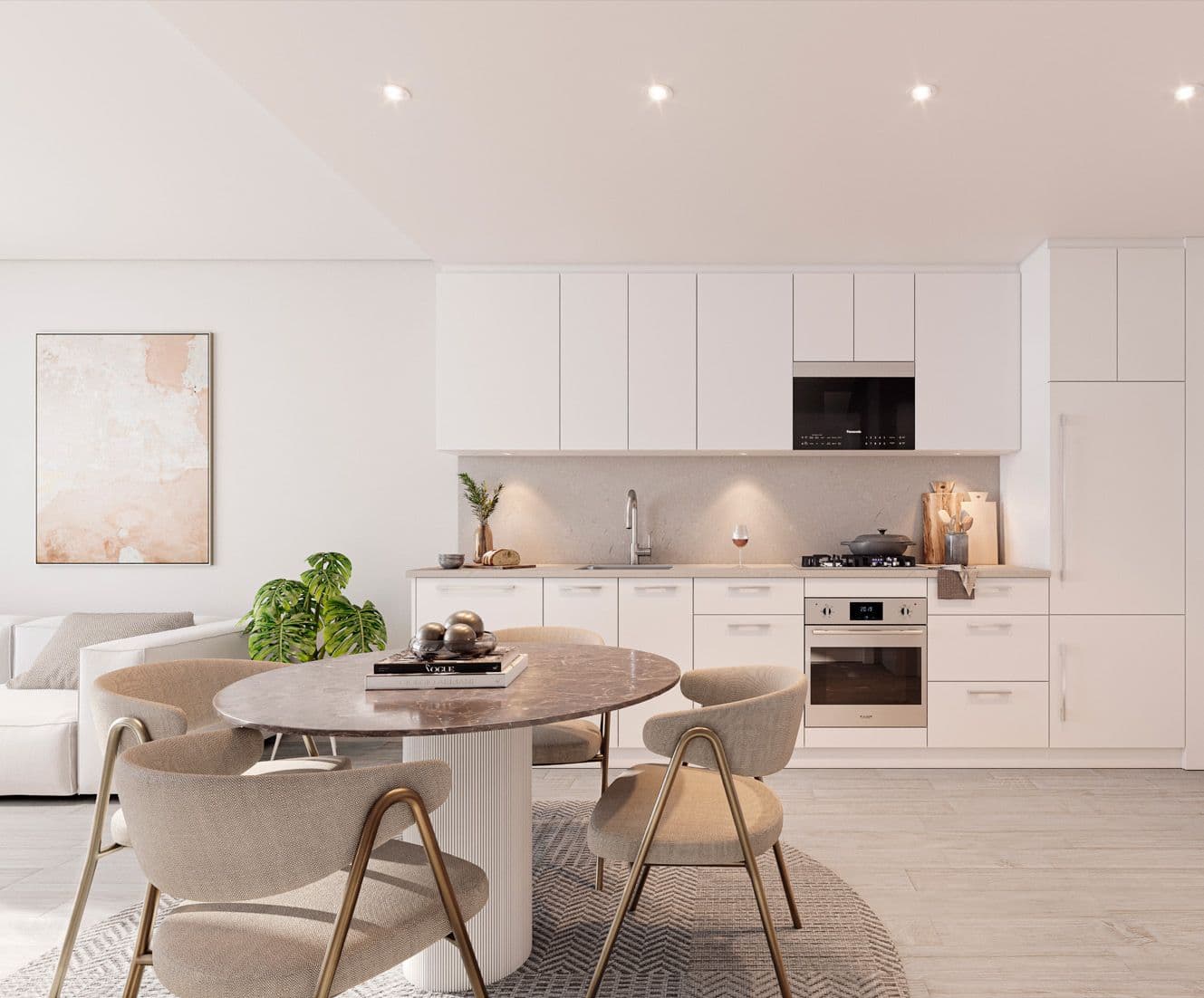 Perla Condos – An open kitchen and dining area with white cabinetry, a round marble dining table with beige upholstered chairs, and a framed abstract print on the wall.