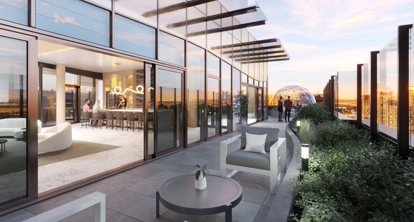 Perla Condos – A rooftop terrace at dusk with an indoor lounge visible through glass doors, an outdoor seating area, a glass dome structure, and people walking along the walkway with a city skyline view.
