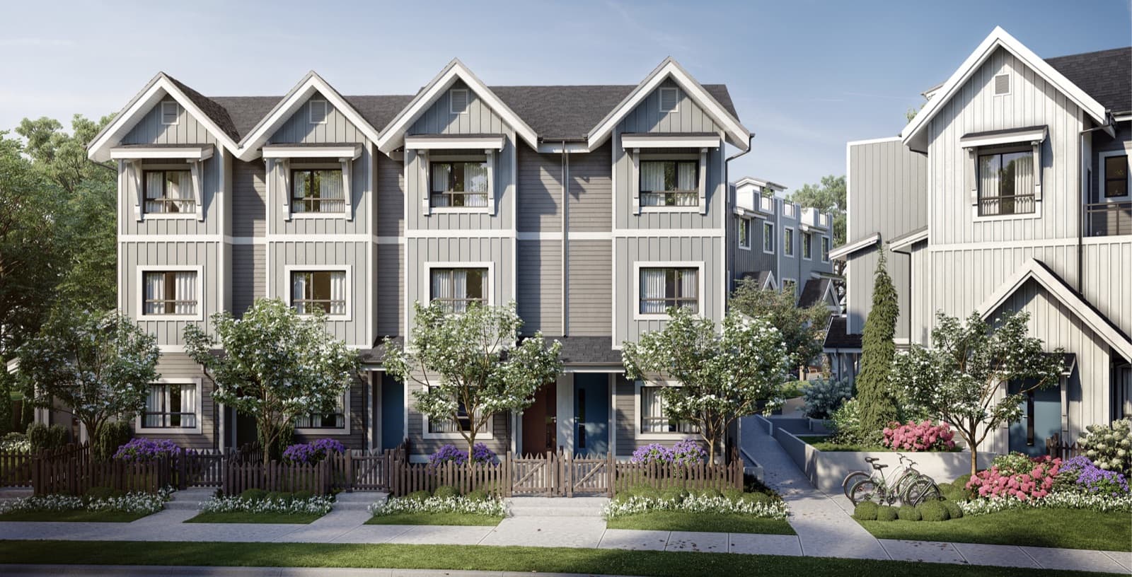 Samer – Rendering of a row of gray and white three-storey townhomes with gabled roofs, front gardens, wood picket fences, and bicycles parked on the walkway.