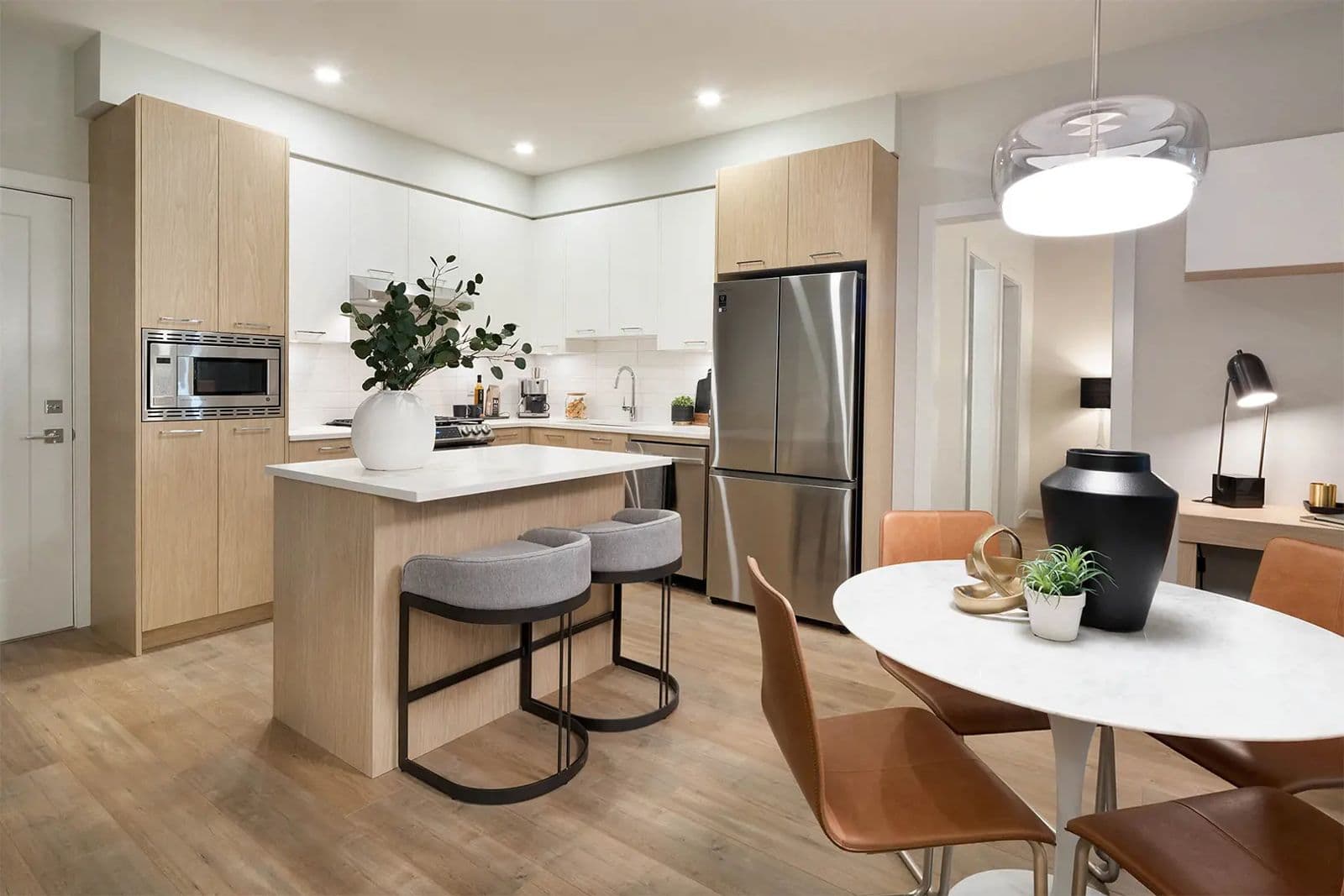 Southaven – Kitchen with light wood and white cabinetry, stainless steel fridge, island seating, and an adjoining dining nook with a round table and desk area.