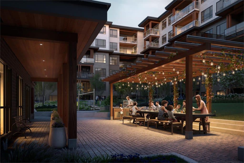 The Oaks Phase 3 (Willow) – An evening view of a courtyard patio with string lights over a wooden pergola and people dining together at outdoor tables.