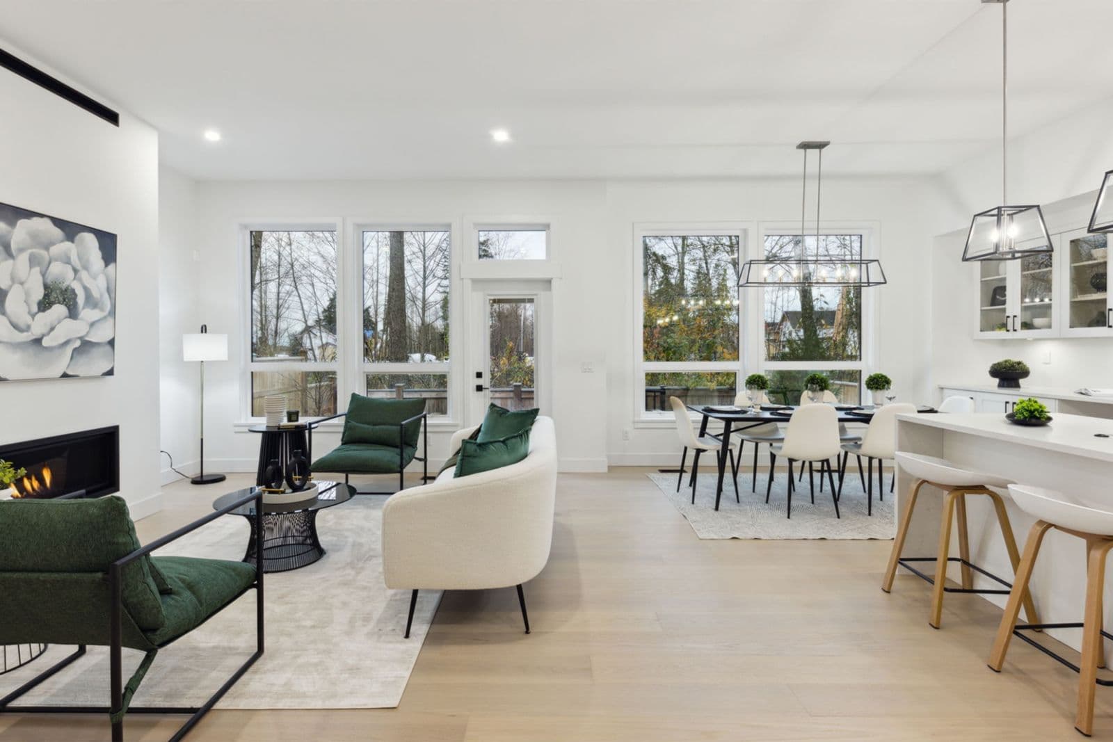Brighton North – Spacious main living and dining layout with light wood flooring, fireplace, contemporary green chairs, and large windows.