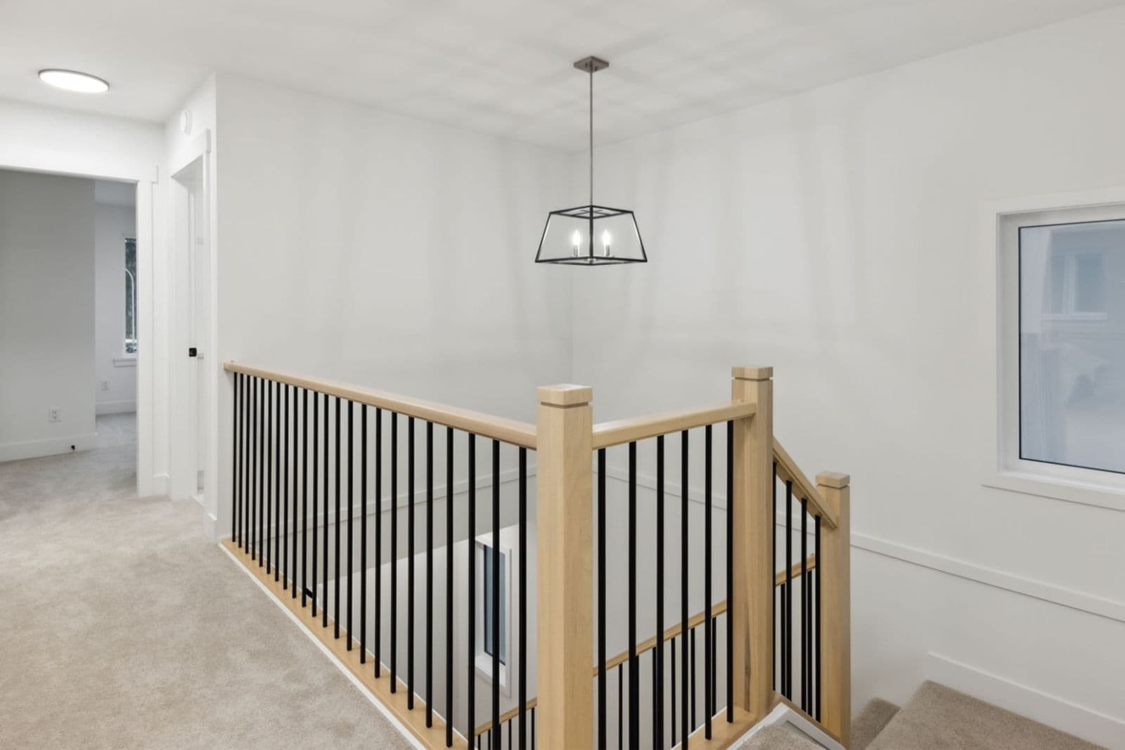 Brighton North – Upper landing hallway with carpeted flooring, wooden handrail with black metal spindles, and a modern pendant light.