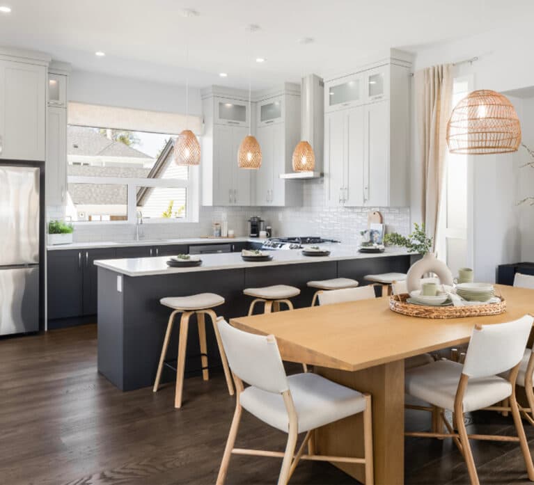 Brighton North – Open-concept dining space and kitchen with a dark grey island, woven basket pendant lights, and wooden dining table set.