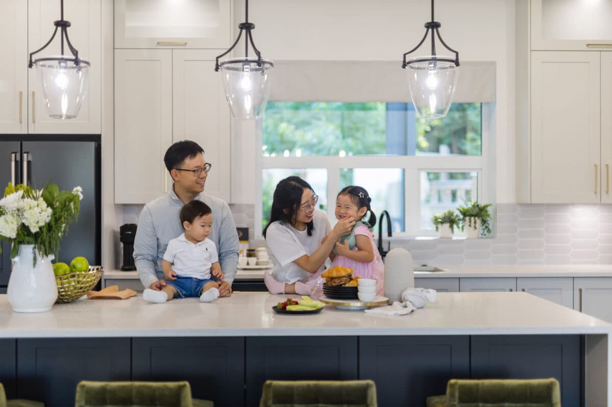 Brighton North – Family with two young children seated around a kitchen island with white countertop and dark cabinetry.