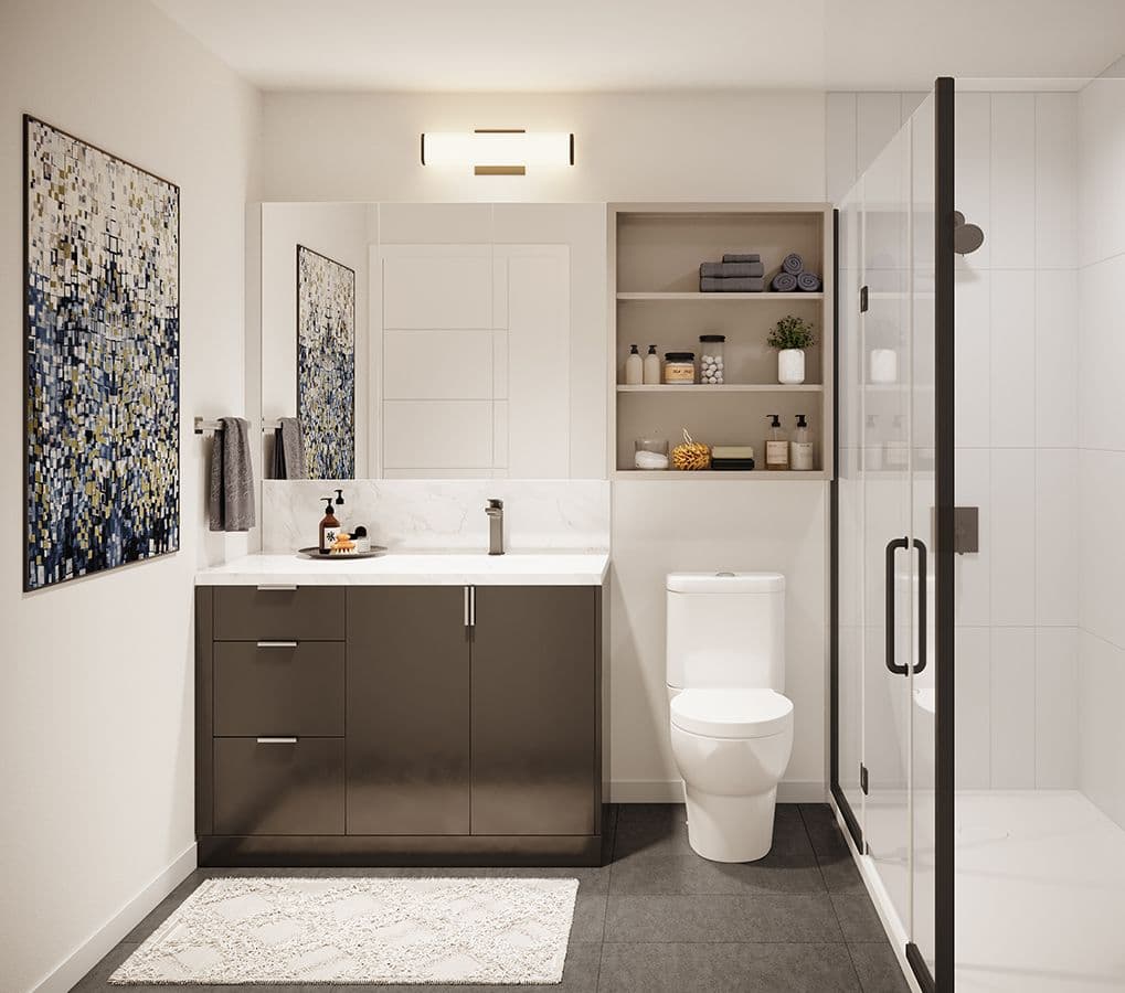 Linc Condos – This modern bathroom features a dark gray vanity with a white countertop, a sleek toilet, and a glass-enclosed walk-in shower framed in black. Open shelving above the toilet provides neat storage for toiletries, while dark floor tiles and a colorful abstract wall painting complete the bright, clean aesthetic.