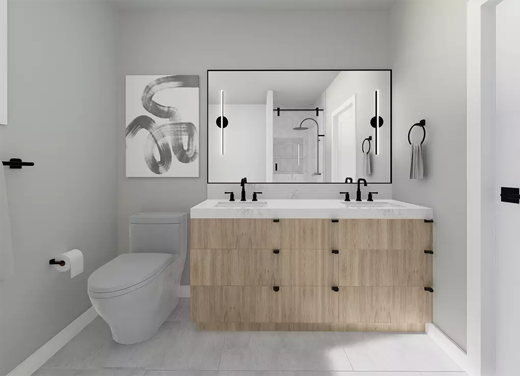 Uptown Cedar – A modern bathroom featuring a floating light-wood double vanity with white countertops, matte black fixtures, and a large illuminated mirror. Light gray walls, a toilet, soft tiled floors, and abstract black-and-white artwork complete the minimalist design.