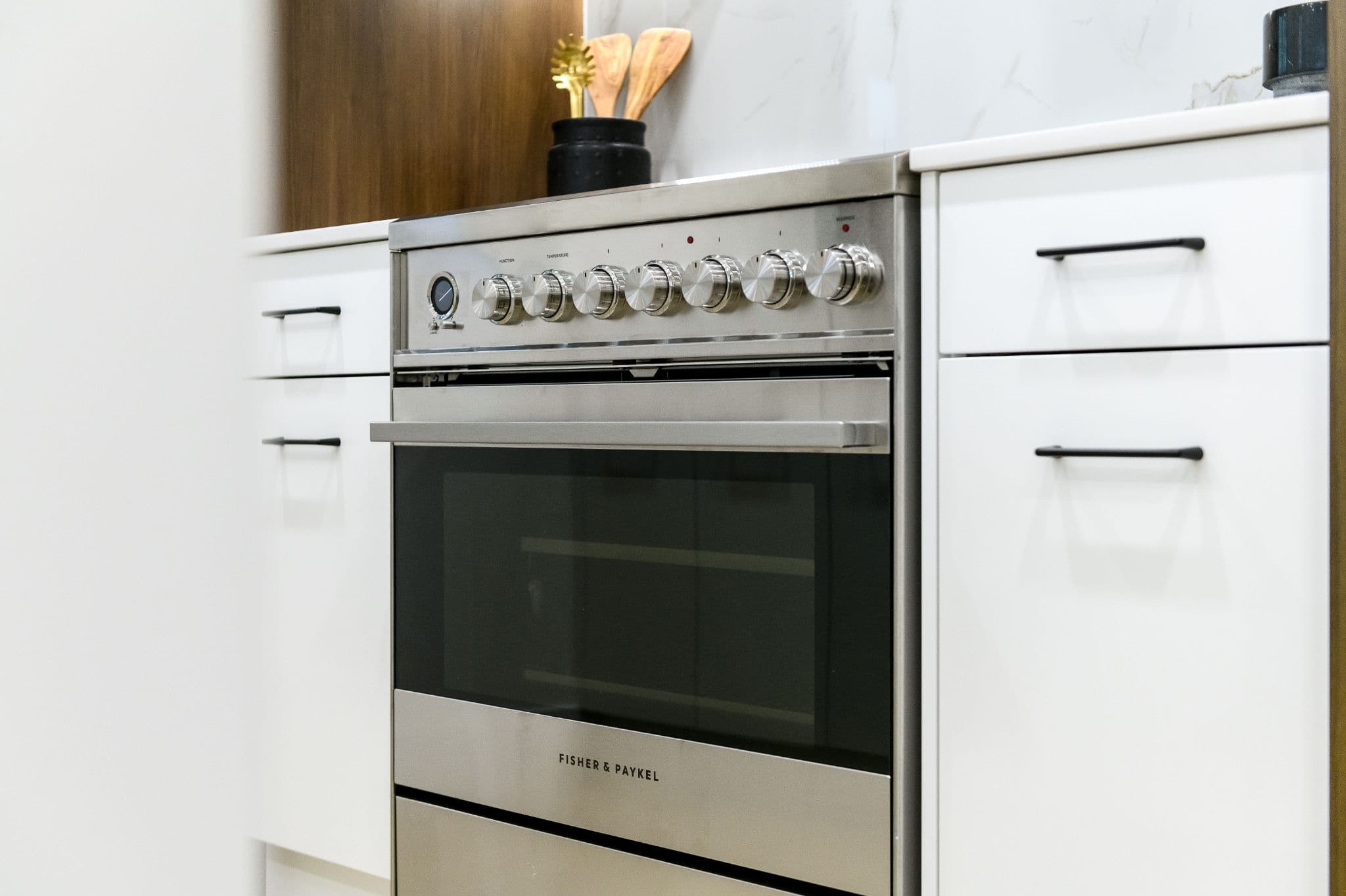 Aria 2 – Close-up of a stainless steel Fisher & Paykel oven range with dial controls, built into white cabinetry.