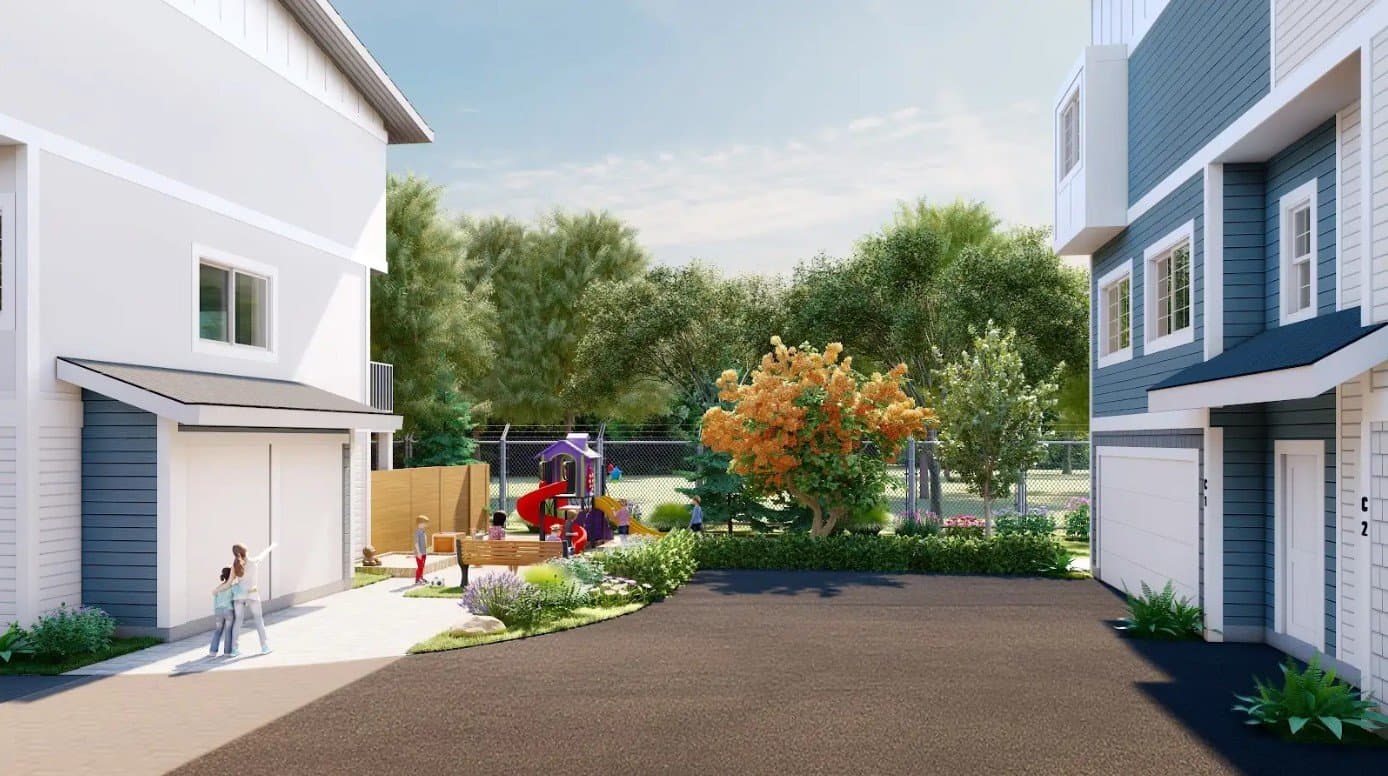 The Signature – A sunny outdoor community playground nestled between modern multi-story townhomes with white and blue siding. The shared space features a colorful play structure with slides, a sandbox, landscaped shrubbery, and mature green trees along a fenced perimeter.