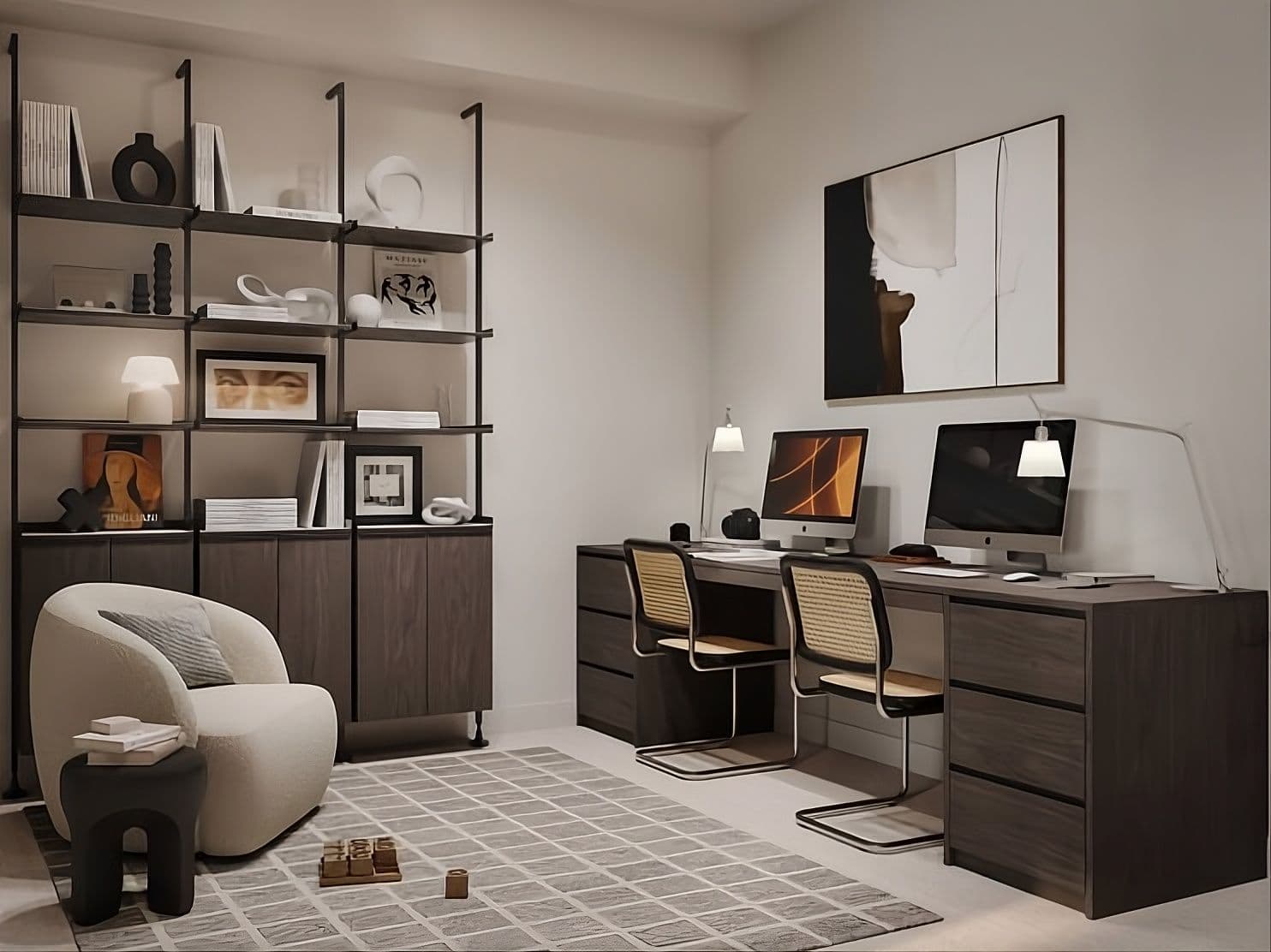 Atlin – A modern home office setup featuring a dark wood double desk equipped with two computer monitors, desk lamps, and cane-back chairs. Across from the workspace is a tall floor-to-ceiling dark wood shelving unit filled with books and art objects, complemented by a cozy cream armchair and a patterned area rug.