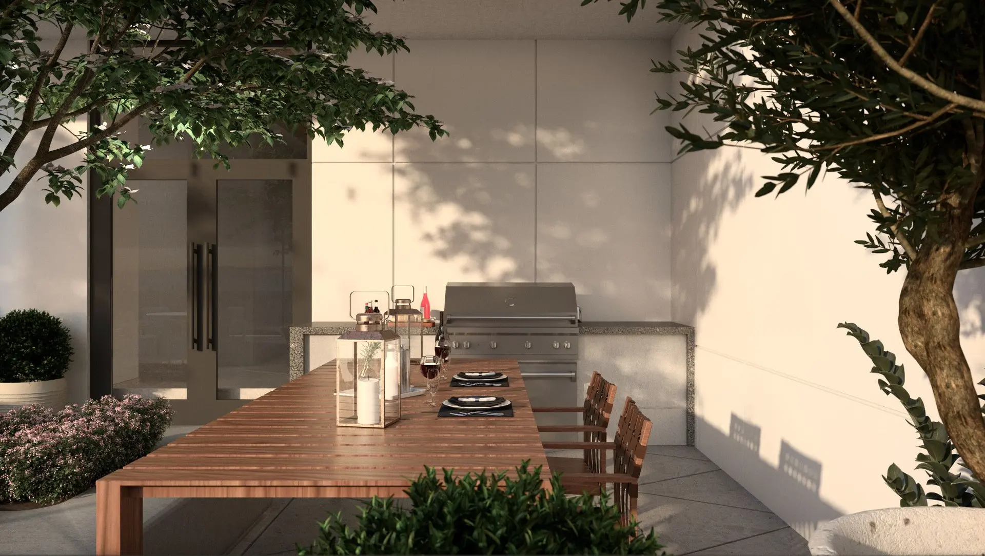 Elmwood – An outdoor patio dining and BBQ area features a built-in stainless steel grill set against a stone counter and light-paneled wall. A long wooden dining table is set with placemats, wine glasses, and candle lanterns, surrounded by potted trees and shrubbery in warm natural sunlight.