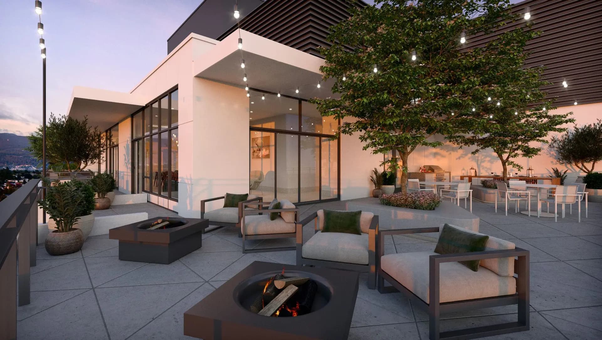 Elmwood – A modern outdoor rooftop terrace featuring stone pavers, armchairs arranged around black fire pits, and an open-air dining area beneath leafy trees. Overhead string lights, glass railings, and expansive floor-to-ceiling windows connect the patio to an indoor lounge against a twilight sky.