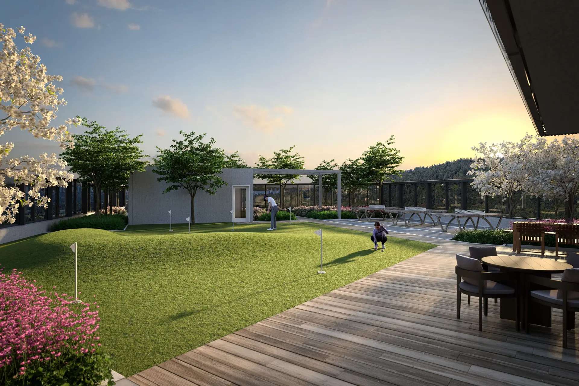 Elmwood – A landscaped outdoor rooftop terrace features a rolling putting green with mini golf flags, ping-pong tables, and a wooden deck with patio dining furniture. Flowering trees, lush garden beds, and views of a forested hillside frame the space beneath a warm sunset sky.