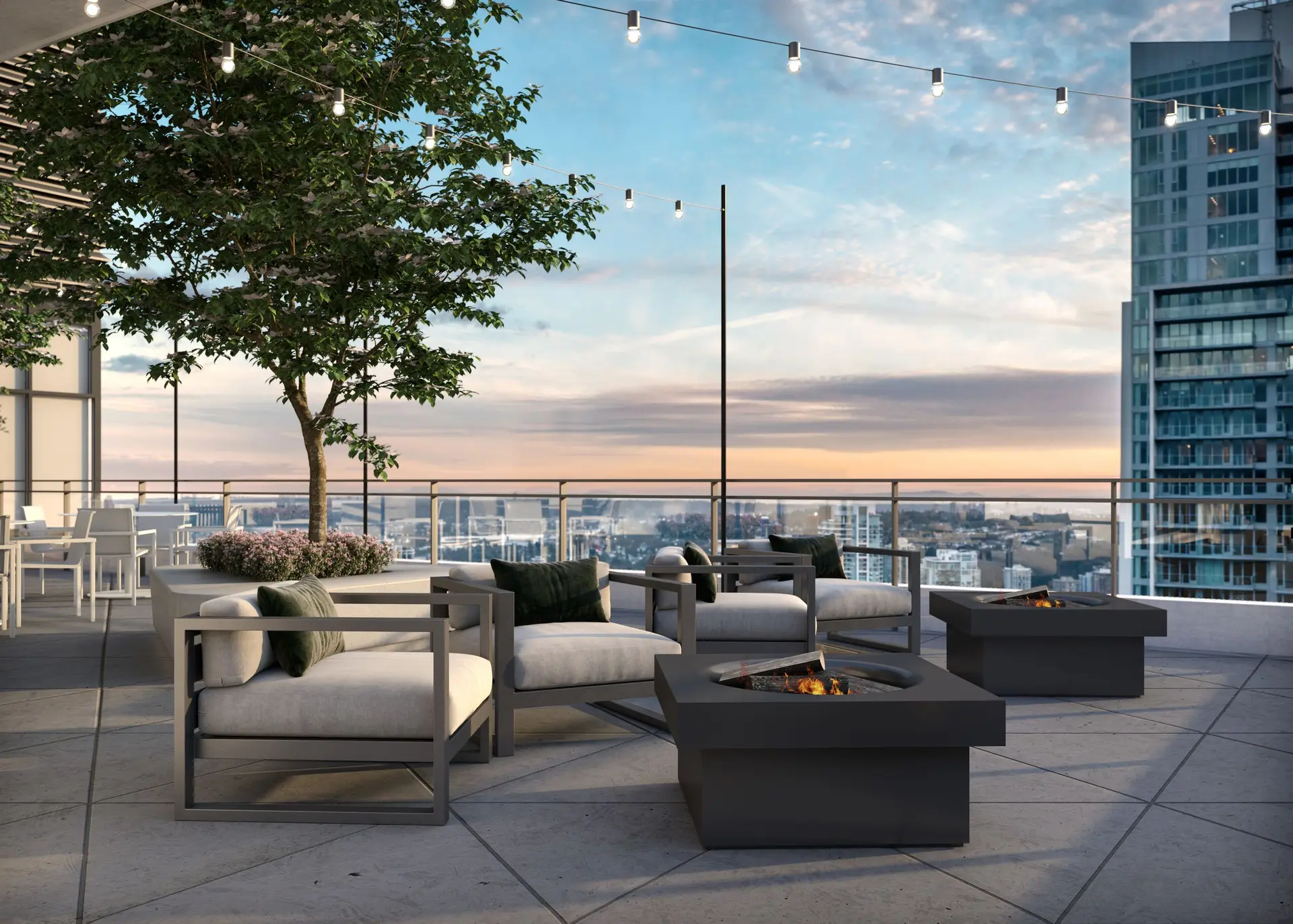 Elmwood – A high-rise outdoor rooftop terrace features modern lounge chairs arranged around square fire pits, framed by string lights and a potted tree. Glass railings offer expansive city skyline views under a soft sunset sky.