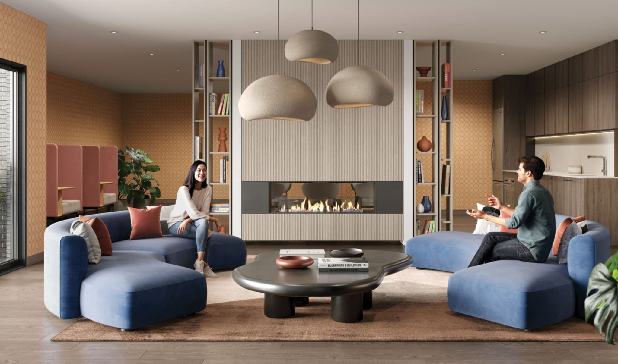Matteō – Indoor resident lounge with a fireplace flanked by bookshelves, blue curved sofas, pendant lighting, and a small kitchenette in the background.