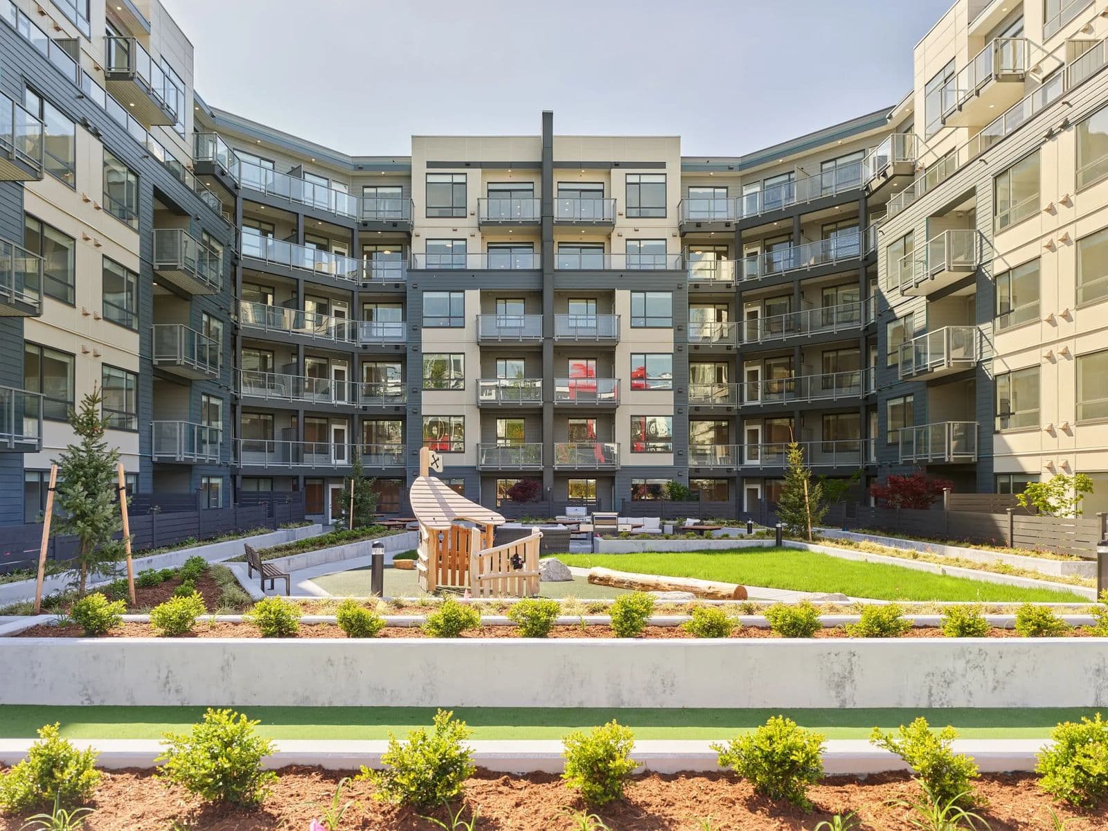 The Hive 2 – Interior courtyard with a children's play structure on artificial turf, an outdoor lounge and BBQ area, and surrounding balconies of the building.
