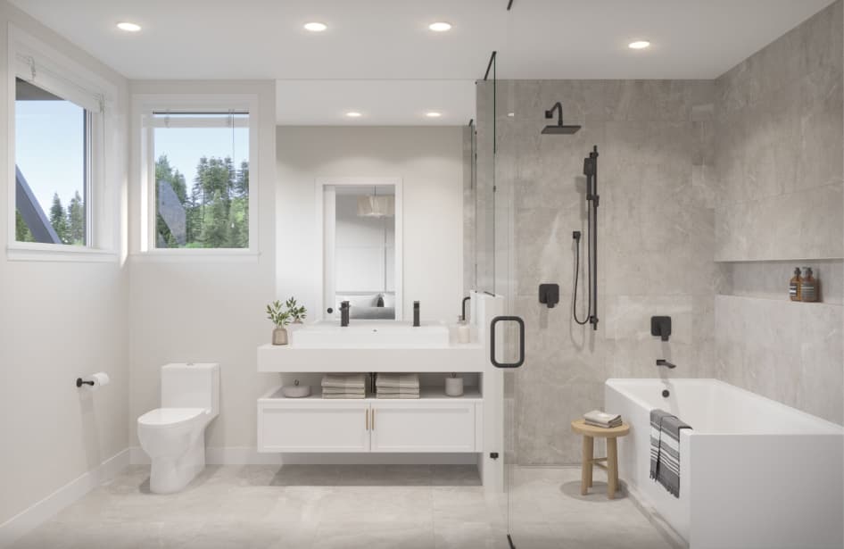 Grovemont – A bright, modern bathroom featuring a floating white vanity with matte black dual faucets, a toilet, and a glass-enclosed shower alongside a white soaking tub set against soft grey stone tiles. Windows let in natural light with a view of lush evergreen trees, creating an airy and clean aesthetic.