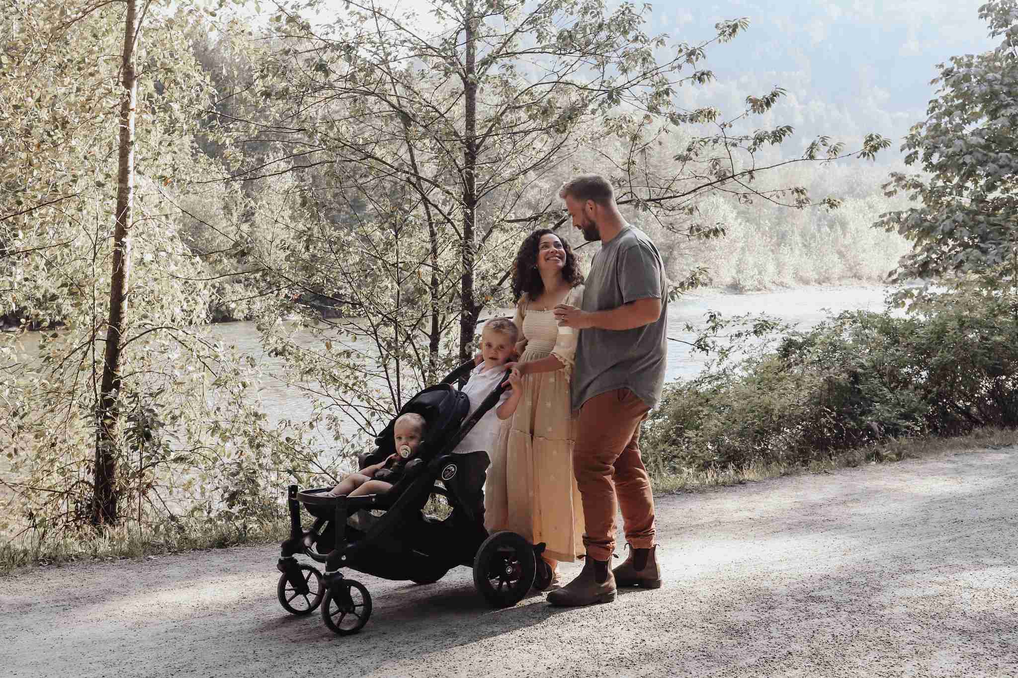 York Residences - Building C – A family of four walks along a gravel riverside path in wooded surroundings; no building from the development is visible in this lifestyle shot.