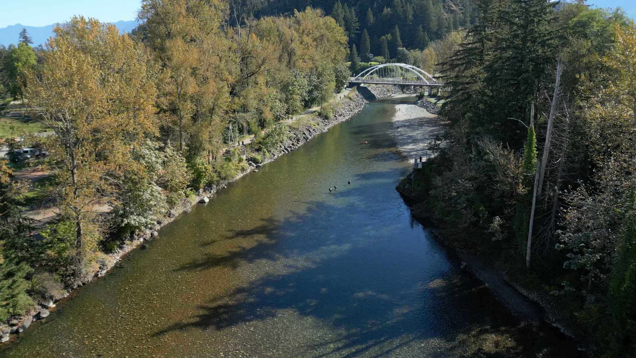 York Residences - Building C – A drone photo of a river valley with a white arched pedestrian bridge, walking paths, and surrounding trees; no building from the development is visible.