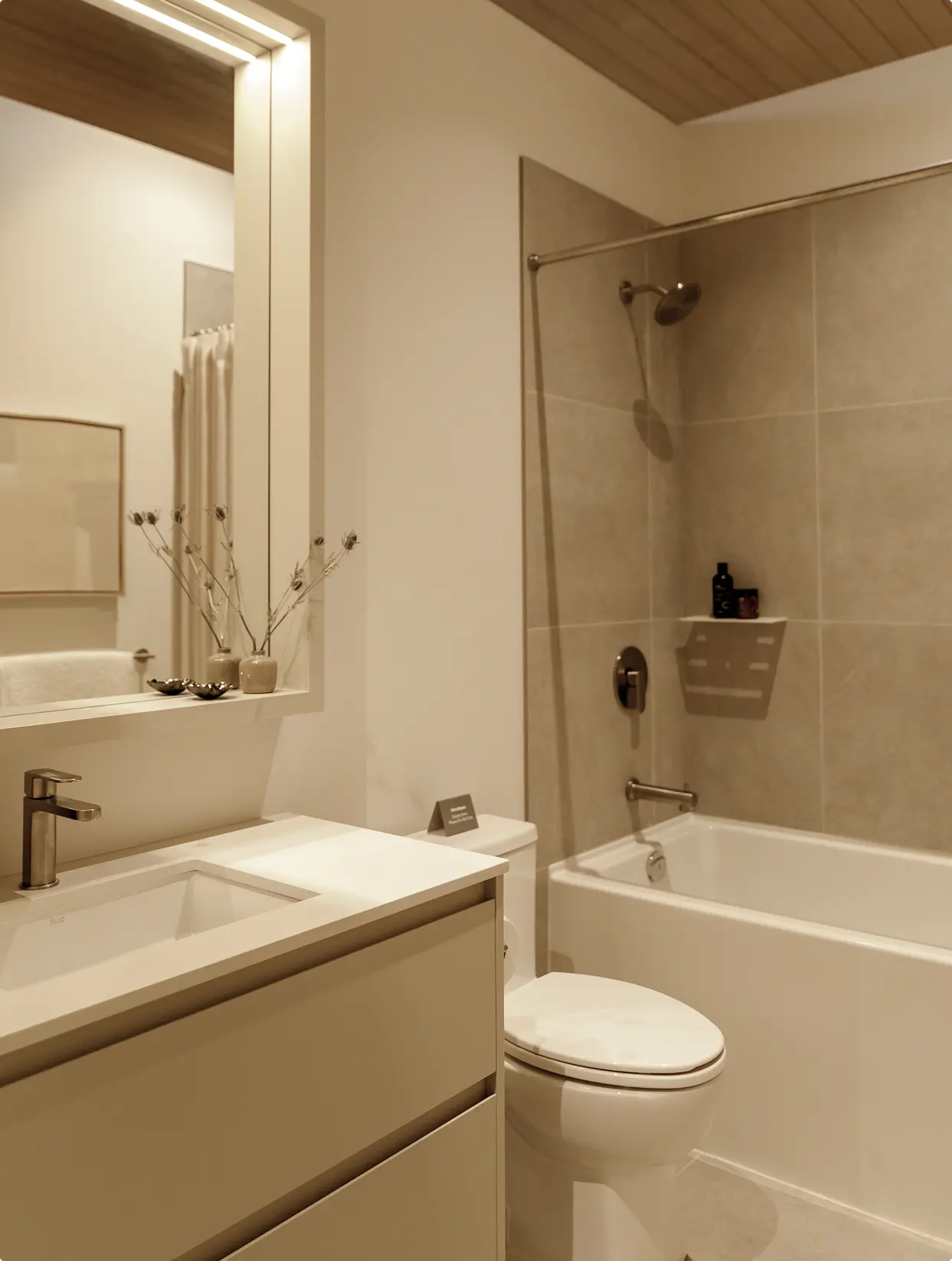 Söenhaus – Bathroom with a white vanity and sink, large mirror, toilet, and a tub-shower combo with beige tile surround and wood-plank ceiling.