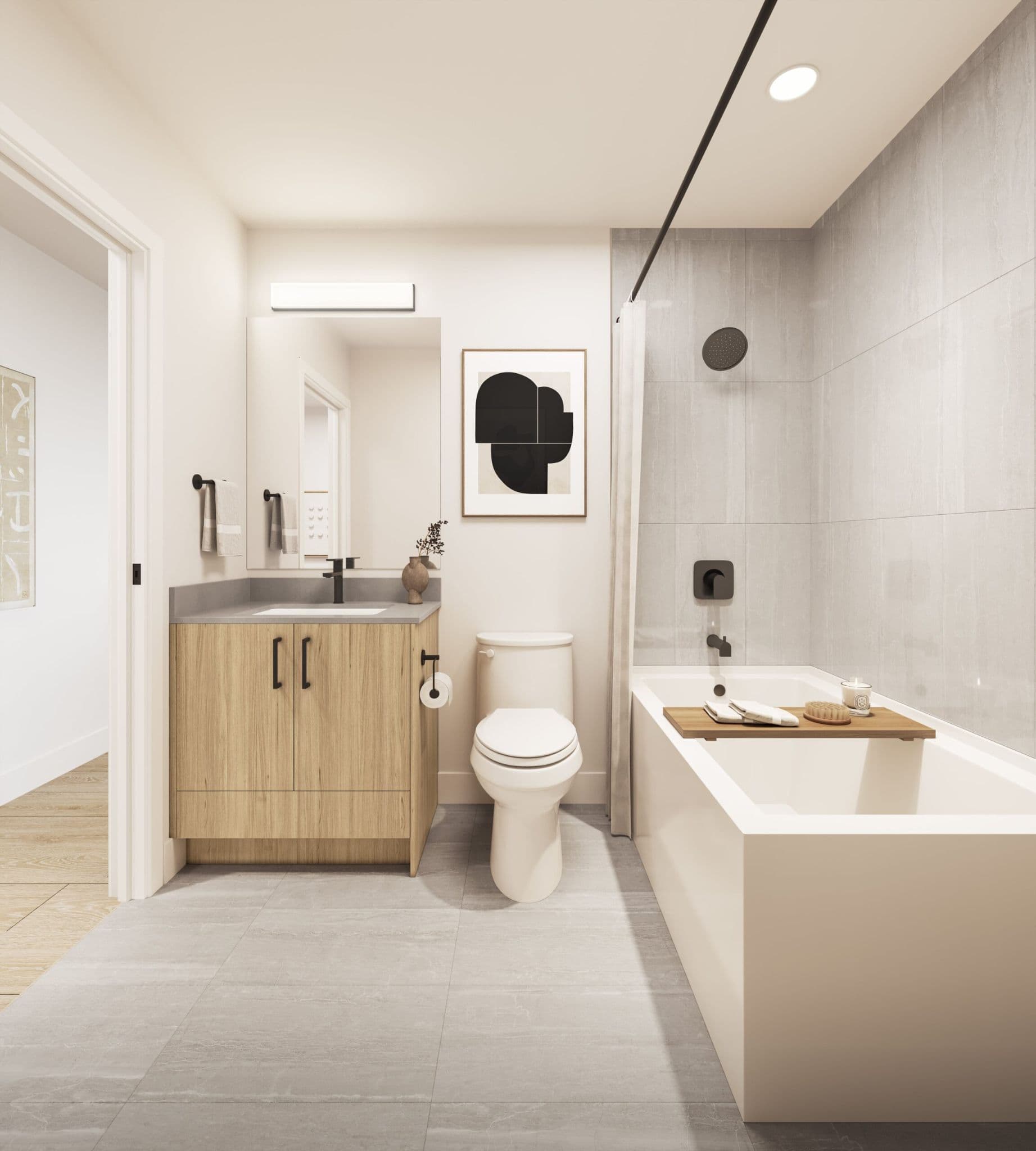 City Corners – A modern, neutral-toned bathroom featuring a light wood vanity with a grey countertop, matte black hardware, and an adjacent toilet. A built-in soaking tub and shower combo is lined with grey vertical tiles and equipped with black fixtures and a wooden bath caddy.