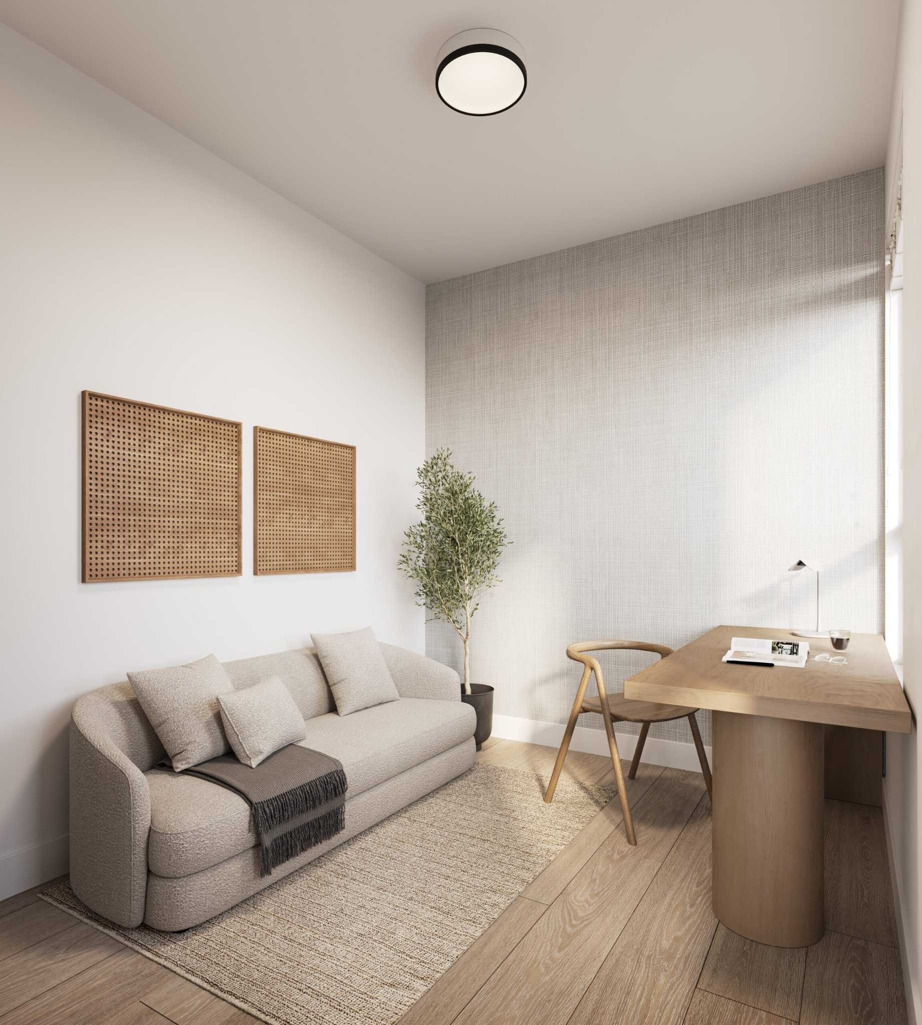 City Corners – A cozy and bright home office space featuring light hardwood floors, a textured gray accent wall, and a curved beige upholstered sofa. Across from the sofa sits a minimalist light wood desk with a matching chair by the window, complemented by a small potted tree and warm, natural sunlight.