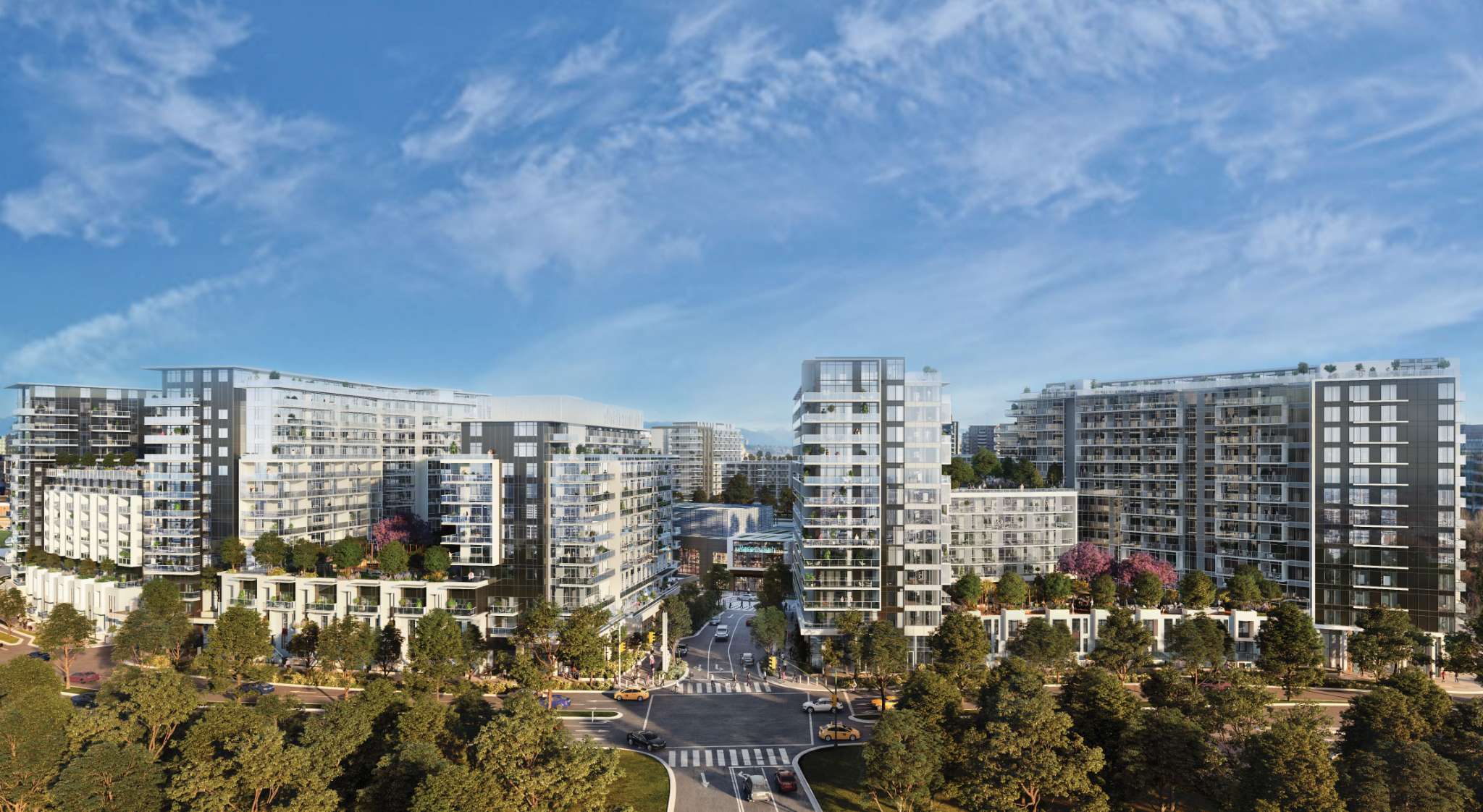 RC at CF Richmond Centre – An elevated aerial view showcases a modern multi-building residential master-planned community with glass-clad towers, podium terraces, and lush green rooftop gardens under a bright blue sky. Tree-lined streets and a central road intersection surround the mid-rise developments, with distant mountain silhouettes visible on the horizon.