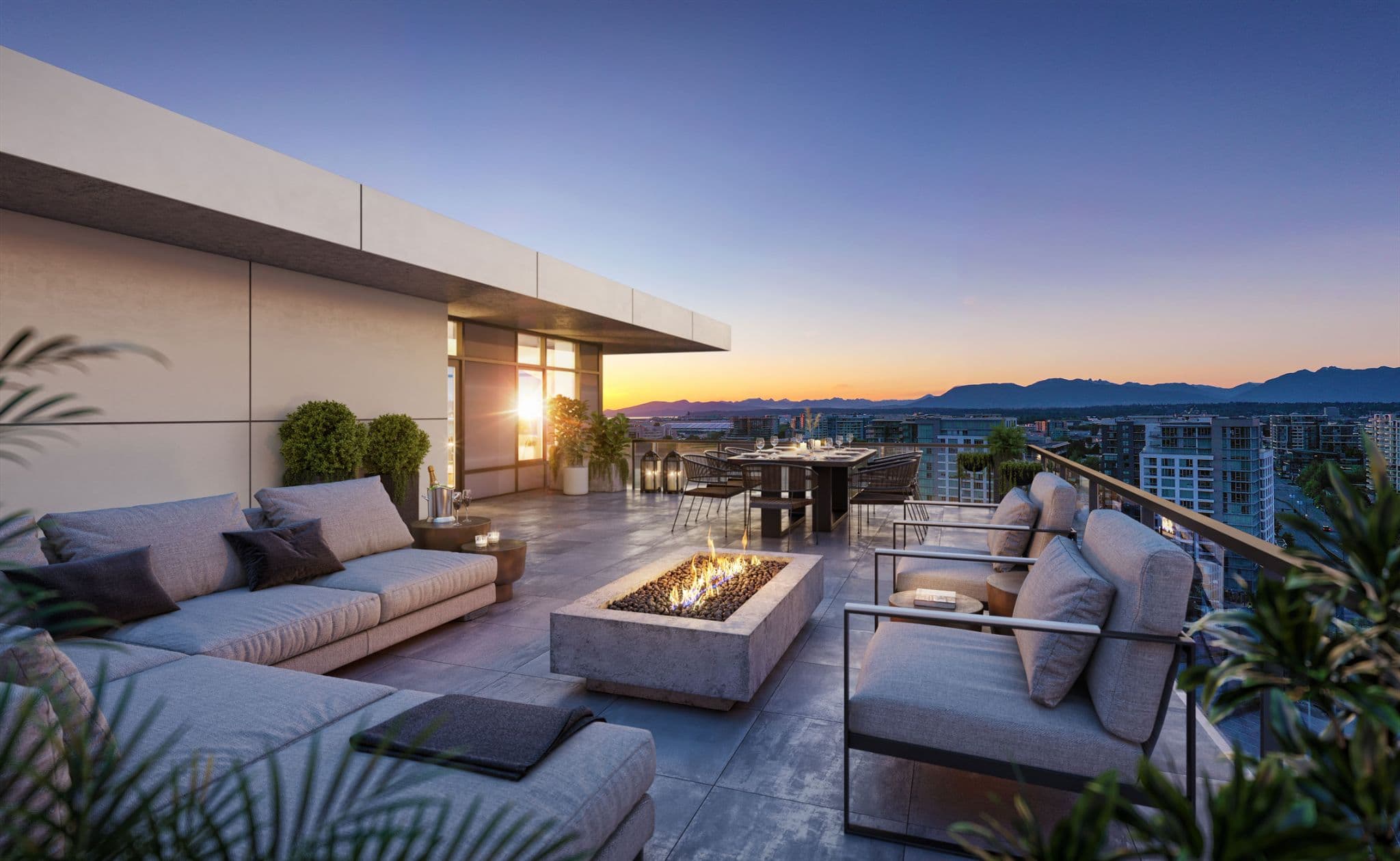 RC at CF Richmond Centre – A luxurious rooftop terrace features a modern concrete fire pit surrounded by plush gray sectional seating and armchairs at sunset. In the background, an outdoor dining setup overlooks a panoramic view of the city skyline, distant ocean, and mountain ranges under a colorful twilight sky.