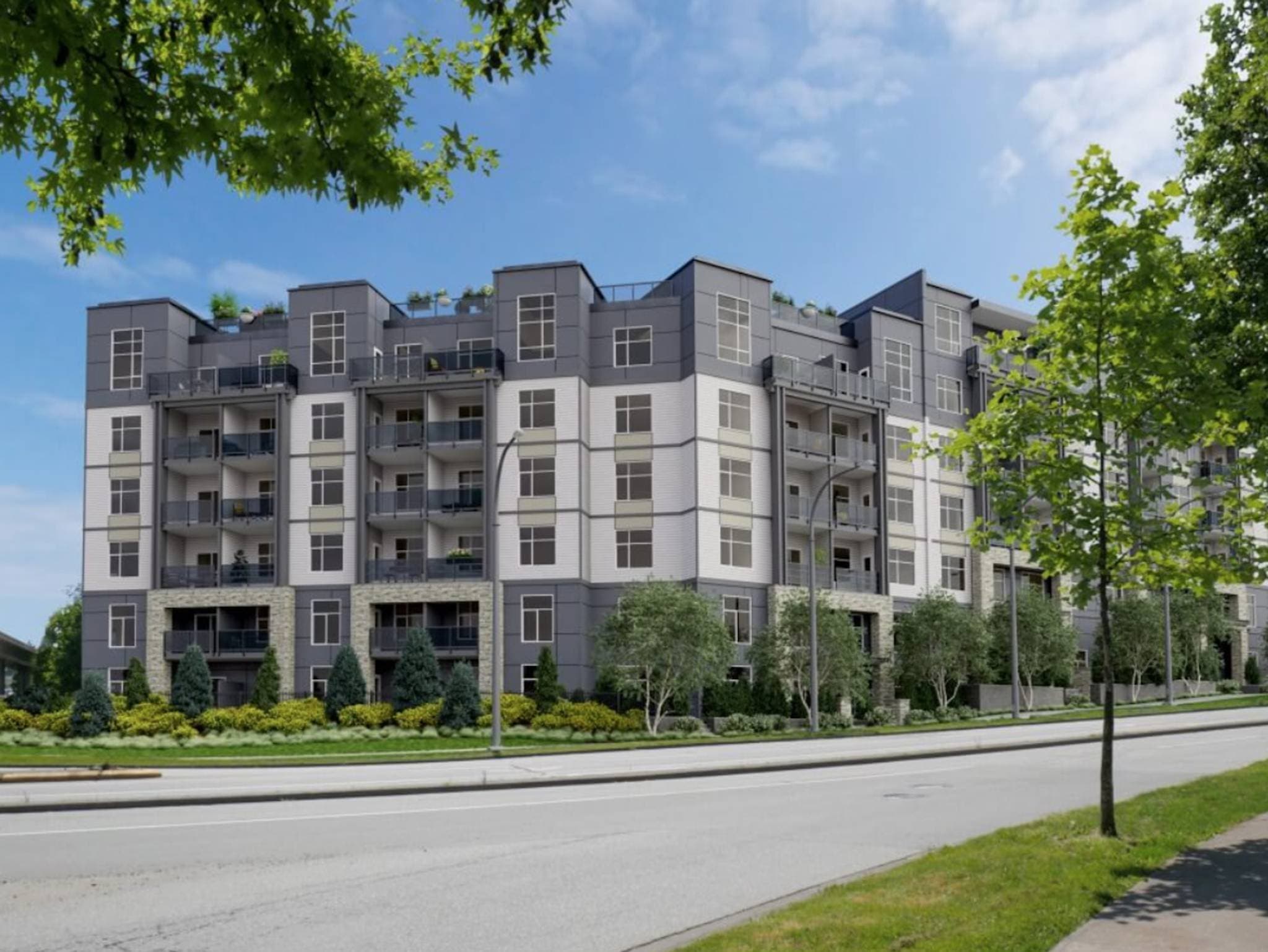 Ledgeview II – A modern multi-story residential building features a facade of dark grey, white siding, and stone accents along the street level. The streetscape is lined with manicured landscaping, young deciduous trees, and a wide roadway under a bright, clear blue sky.