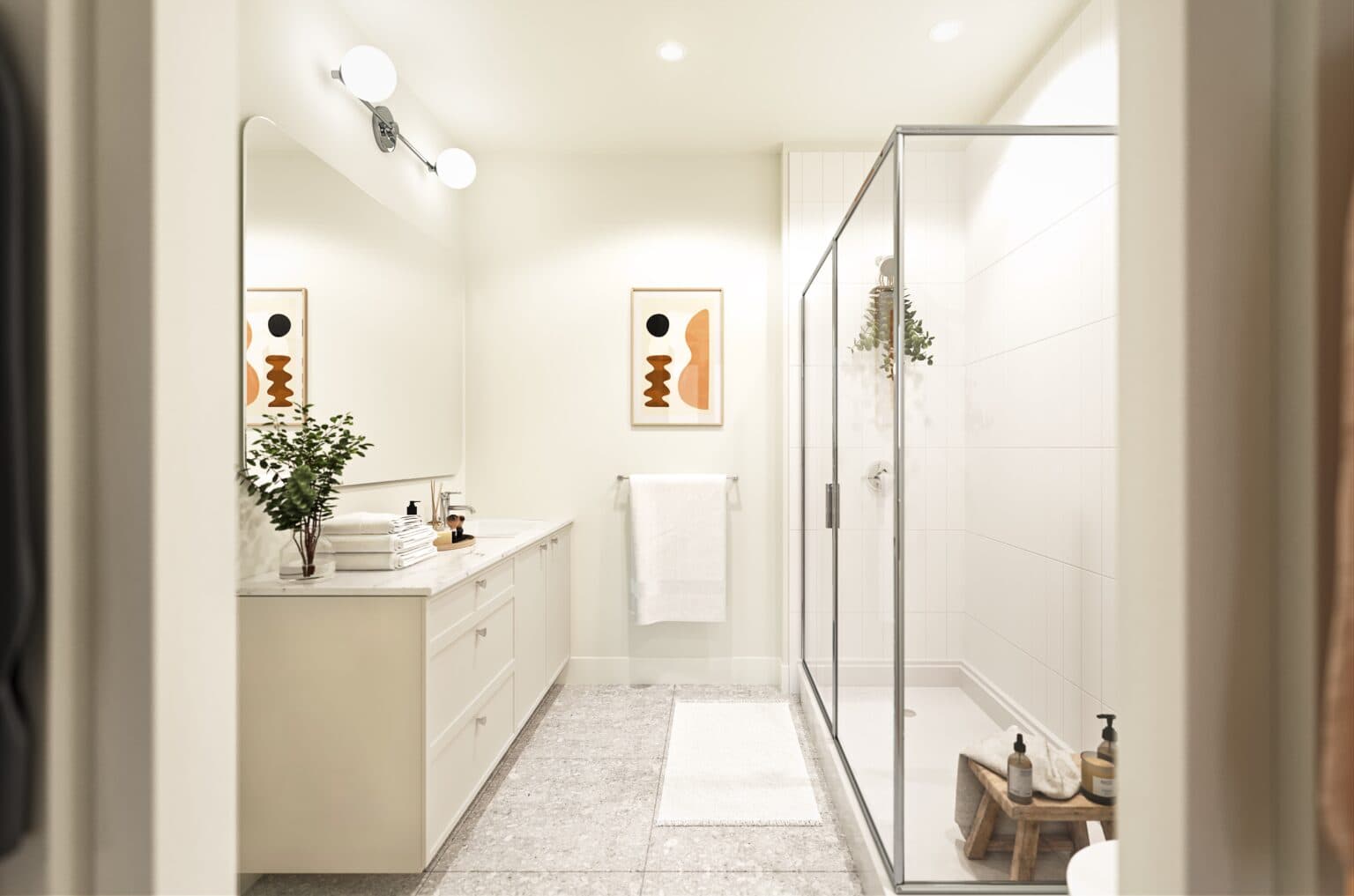 Allison West – A modern, bright bathroom featuring a white vanity with marble countertops, a large framed mirror, and a sleek glass-enclosed walk-in shower. Light stone-look floor tiles, warm minimalist decor, and soft overhead lighting create a clean and tranquil atmosphere.