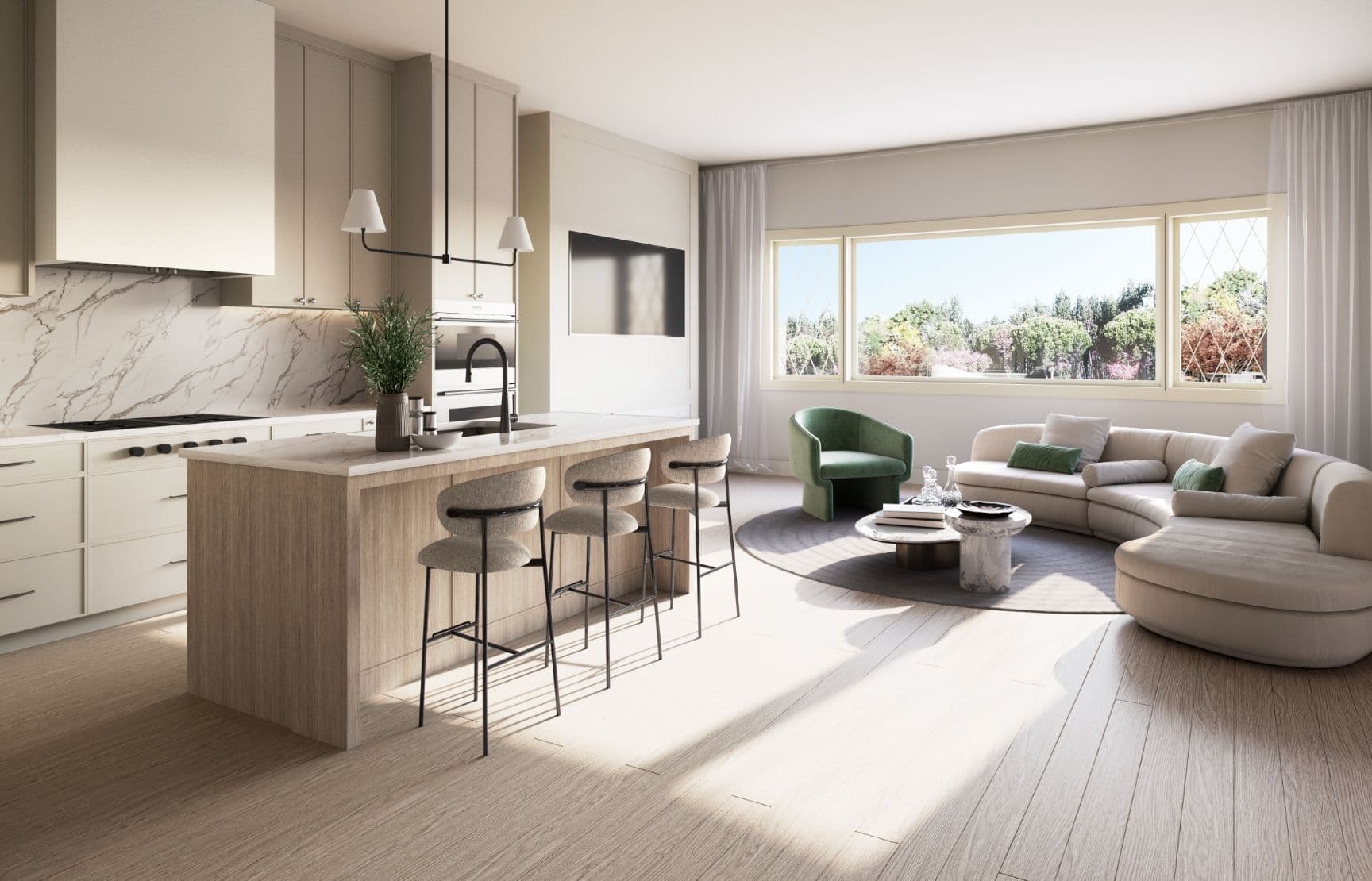 Harlowe House – An open-concept modern kitchen and living room filled with natural light, featuring light wood floors and pale beige cabinetry with marble countertops and backsplash. A curved sectional sofa, green armchair, and kitchen island with three barstools sit beside a large horizontal window looking out onto lush green trees.