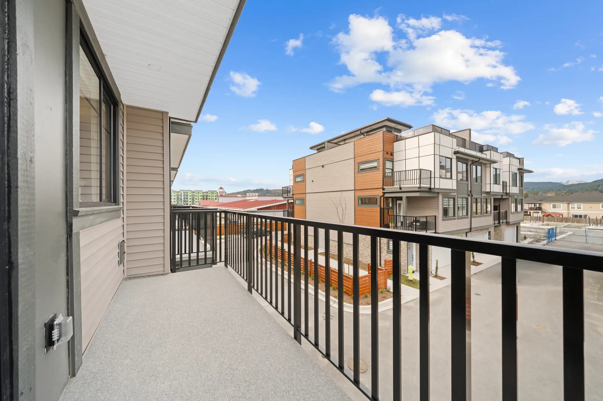 Madison Townhomes – View from a unit's balcony overlooking neighboring townhomes, a shared courtyard, and mountains in the distance.