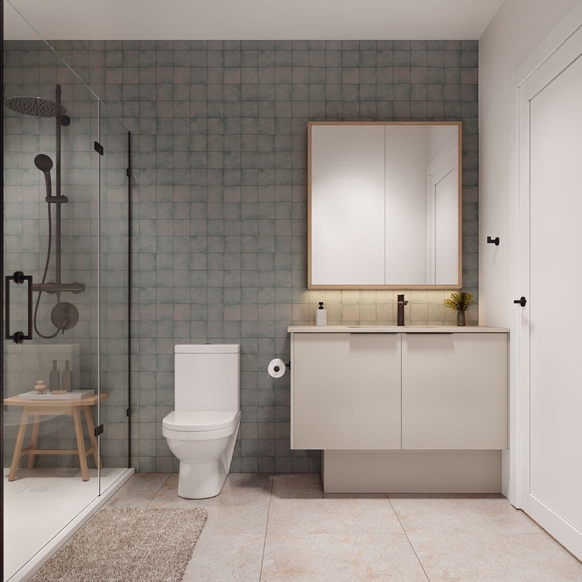 Line House – A modern bathroom features a muted sage-green tiled accent wall, a glass-enclosed walk-in shower with matte black fixtures, and a sleek floating vanity with an underlit wood-framed mirror. Neutral beige floor tiles, a white toilet, and soft, warm lighting create a calm and clean contemporary ambiance.