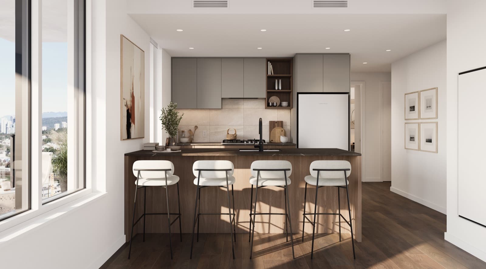 Encore – A modern, open-concept kitchen featuring a dark wood island with a black countertop and four white barstools with black metal legs. The background shows grey upper cabinetry, a light tiled backsplash, integrated appliances, and warm sunlight streaming in from a large window on the left.