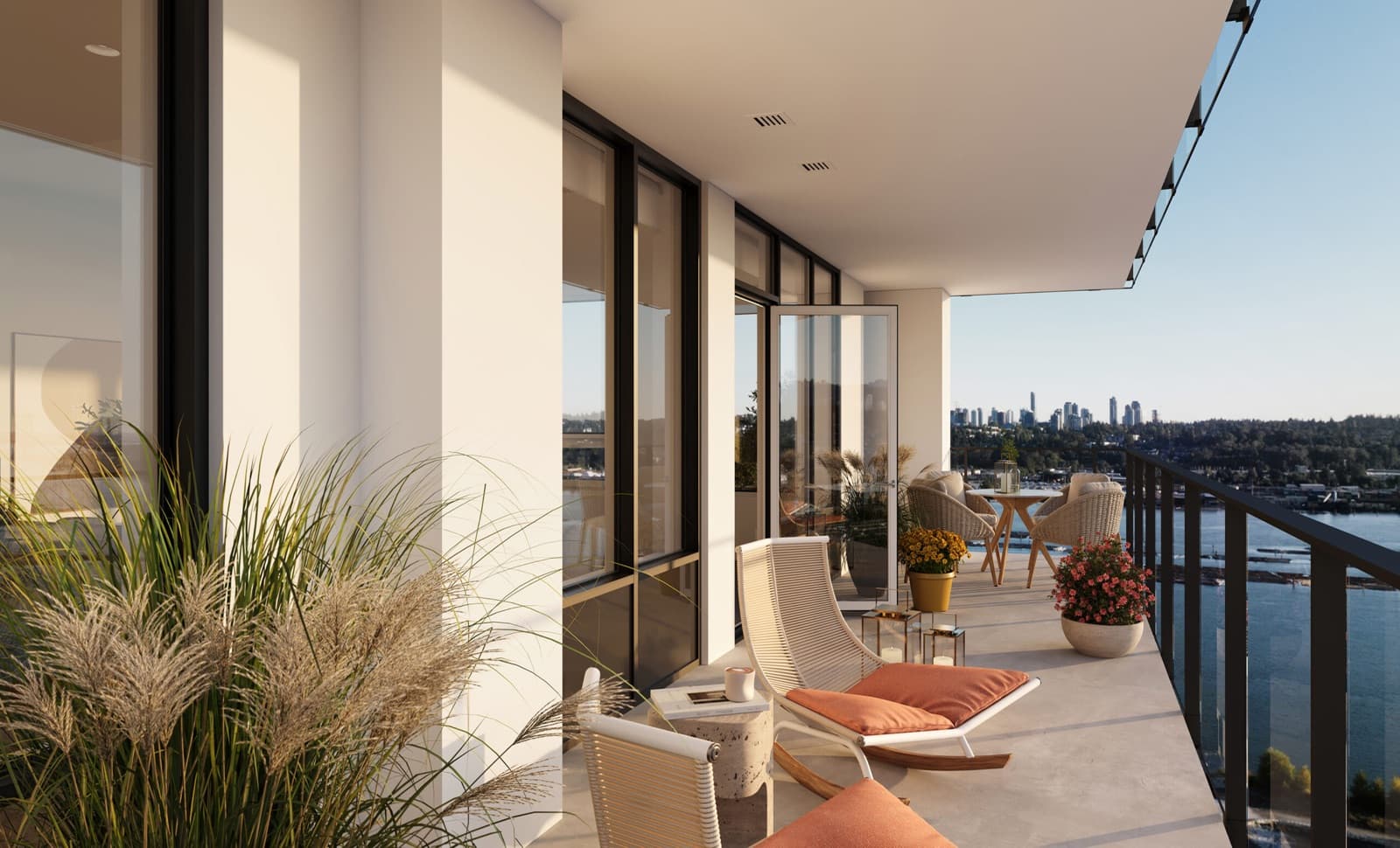 Encore – A spacious, modern high-rise balcony is furnished with stylish lounge chairs, potted plants, and a small dining set, offering a scenic view of a river and a distant city skyline under a clear sky. Warm, late afternoon sunlight bathes the white stucco walls and concrete flooring, creating a serene and inviting outdoor living space.