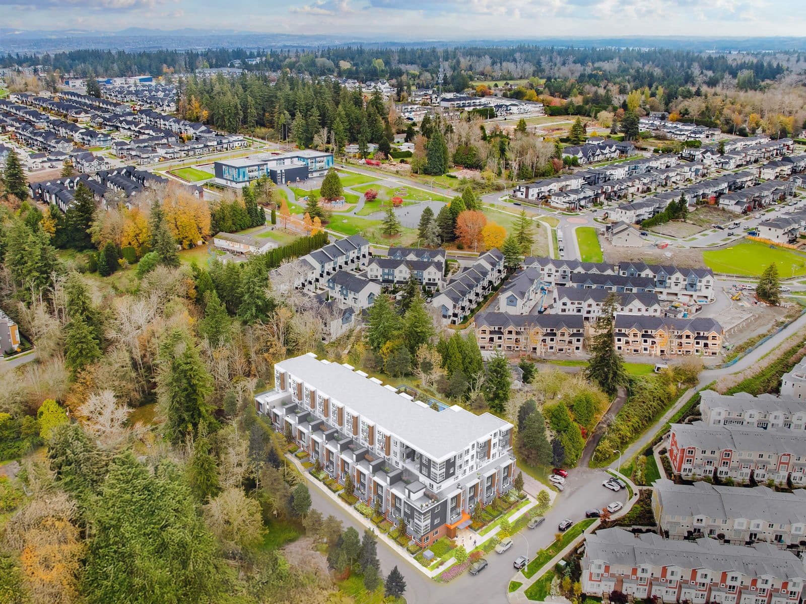 Harlowe – Drone photo looking down on the building's rooftop and surrounding suburban neighborhood with townhomes and trees.