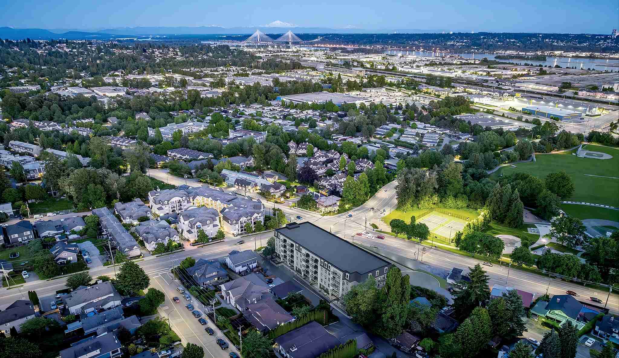 Ravir – Dusk aerial view of the building with a cable-stayed bridge and city skyline in the background.