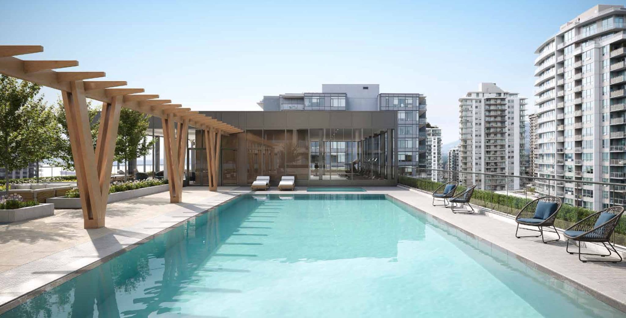 Millennium Central Lonsdale Condos – A rooftop lap pool with lounge chairs and a wooden pergola, surrounded by high-rise towers with city and mountain views.