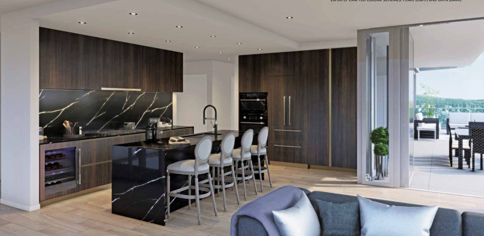 Millennium Central Lonsdale Condos – A dark-toned kitchen with marble backsplash, black built-in oven, wine fridge, and a waterfall island opening to a balcony with dining furniture.