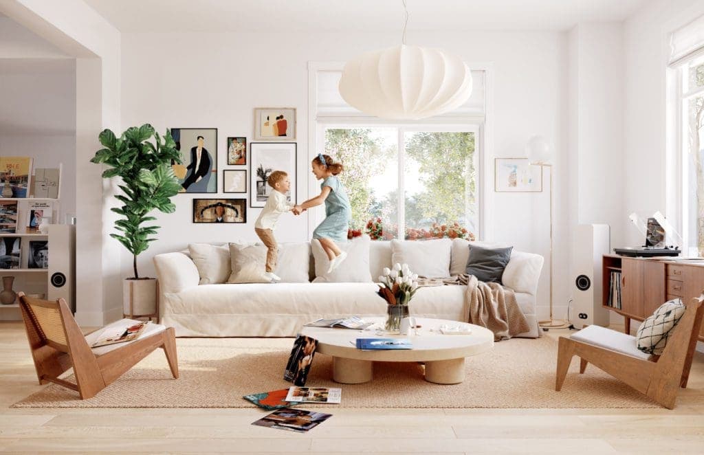 Riley Park – Bright living room with a white slipcovered sofa, wood accent chairs, round coffee table, gallery wall, and two children jumping and playing on the couch.