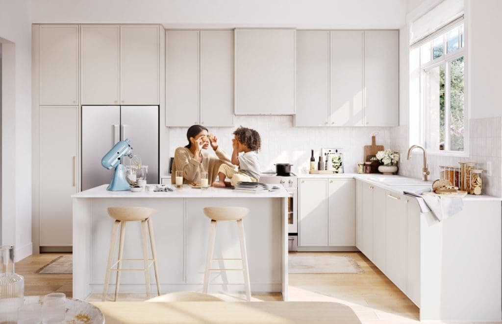 Riley Park – Lifestyle photo of a mother and child at a kitchen island in the same layout but with light beige cabinetry, stainless fridge, and wood barstools.