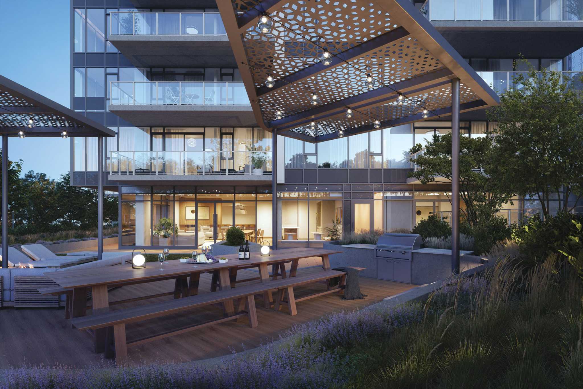 SOCO Two – An outdoor rooftop terrace at dusk with a long communal dining table, built-in BBQ, lounge seating with a fire pit, and a lit indoor lounge visible behind glass.