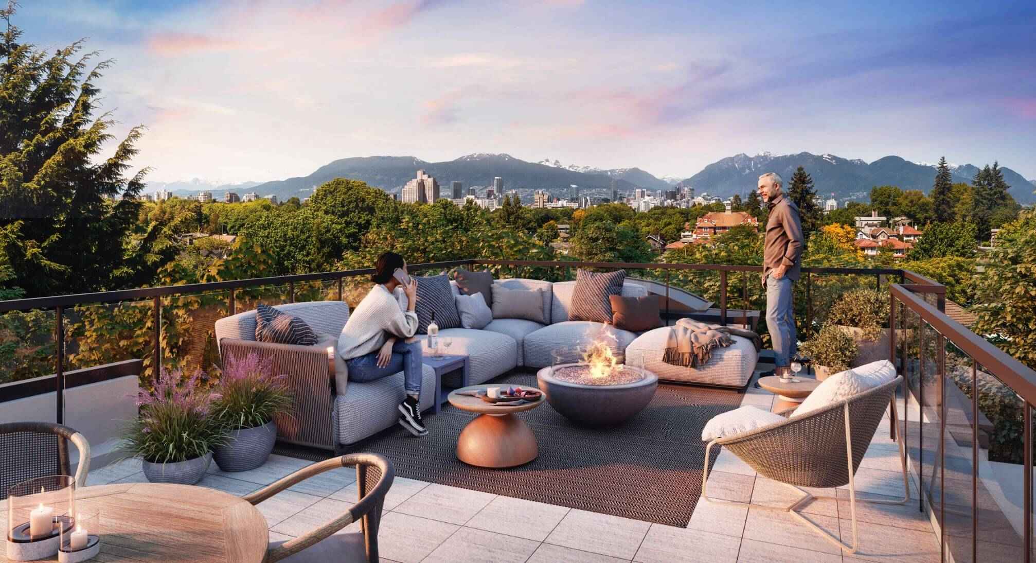 Astrid – A rooftop patio lounge features a plush outdoor sectional surrounding a central burning fire pit with two people relaxing at dusk. The glass-railed terrace overlooks lush green tree canopies, a distant city skyline, and snow-capped mountains under a soft pastel sunset sky.