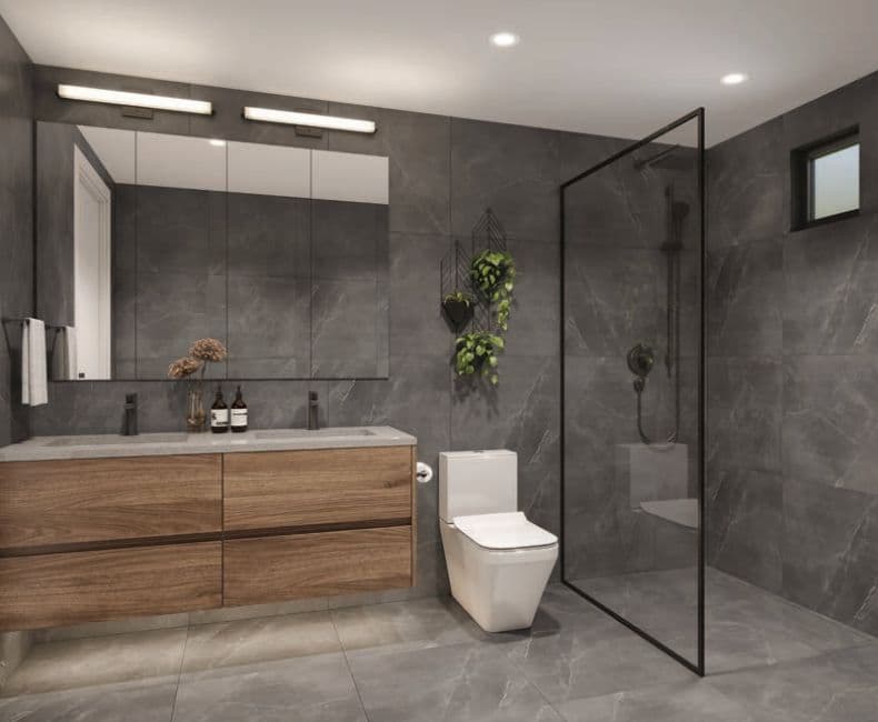 Oakhaus – Rendering of a bathroom with a walk-in glass shower, dark stone tile walls and floor, and a wood vanity with double undermount sinks.