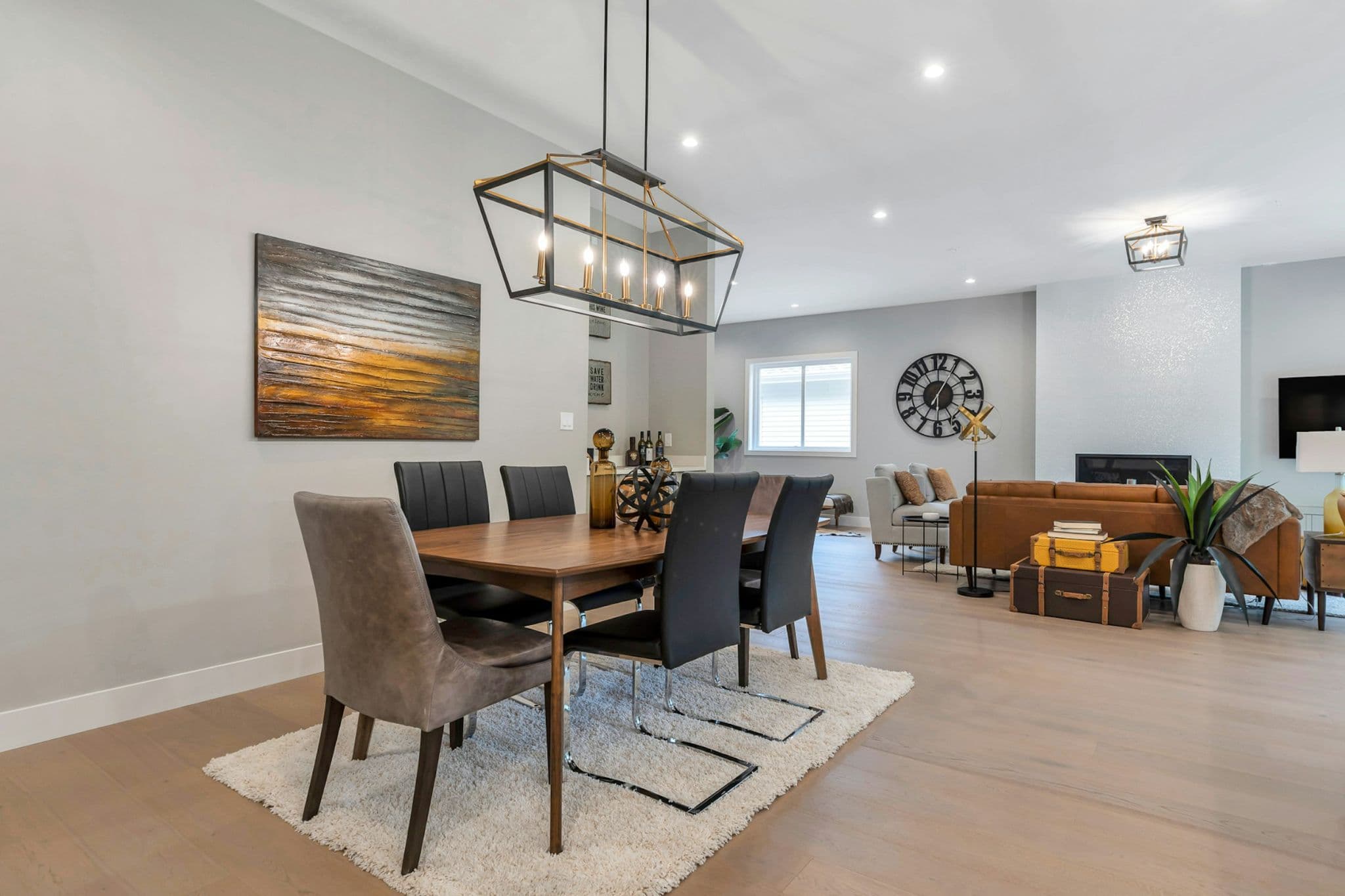 Emerald Ridge – Dining area set with a wooden table, dark leather dining chairs, lantern pendant lighting, and view into the adjoining living room.