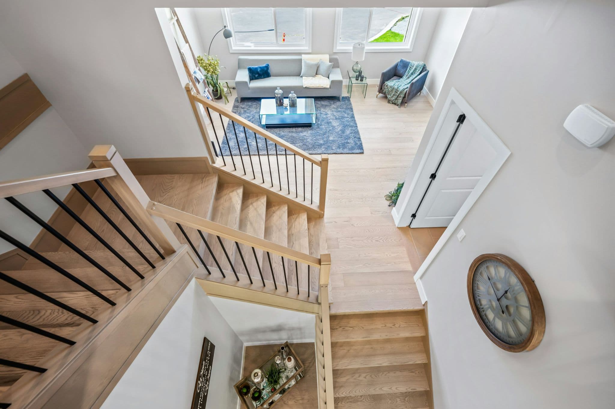 Emerald Ridge – High angle view looking down a multi-flight wooden staircase into a bright living room lounge below.