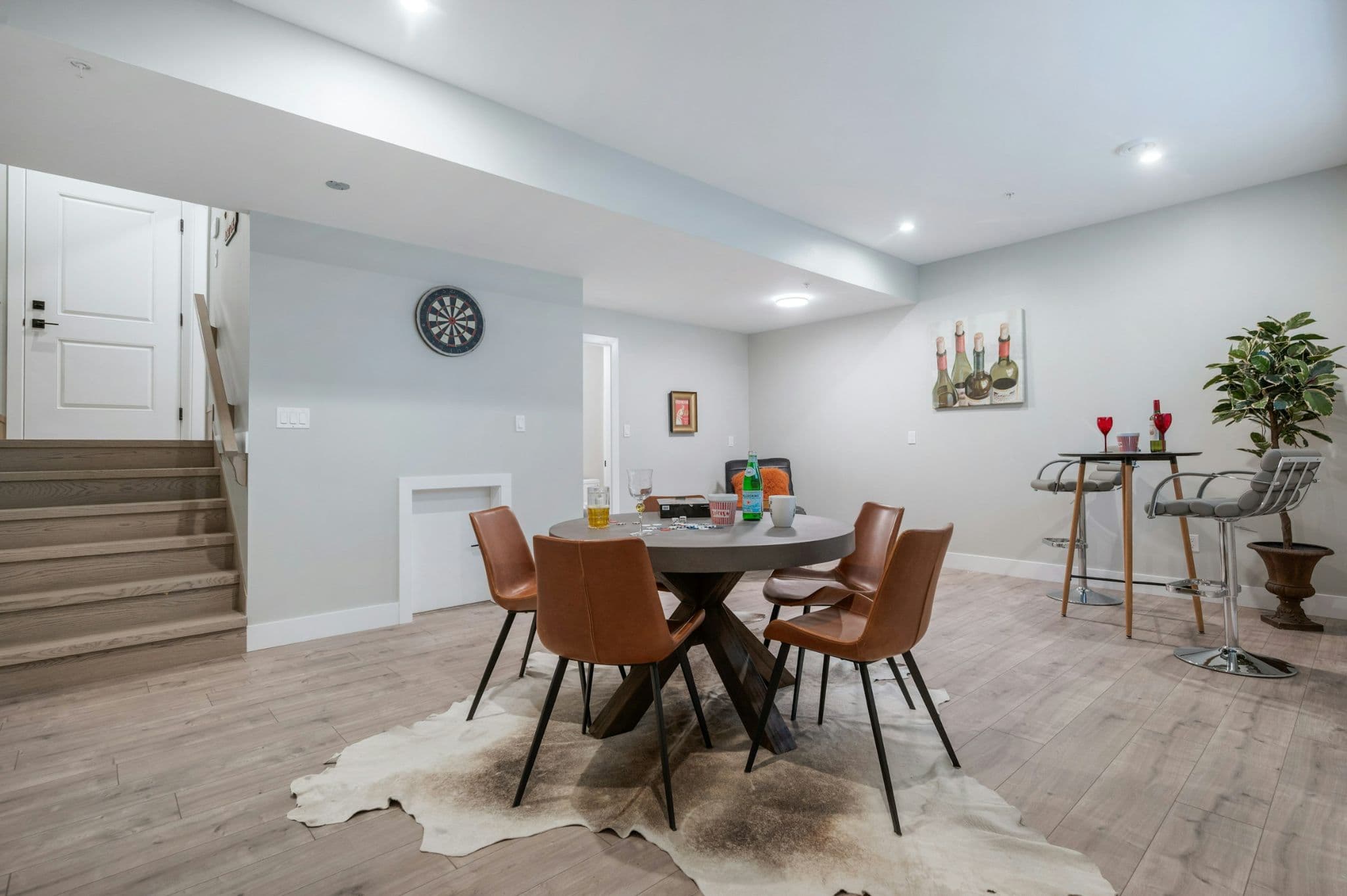 Emerald Ridge – Finished basement recreation room with round poker/game table, brown leather chairs, pub table, and stairs leading down.
